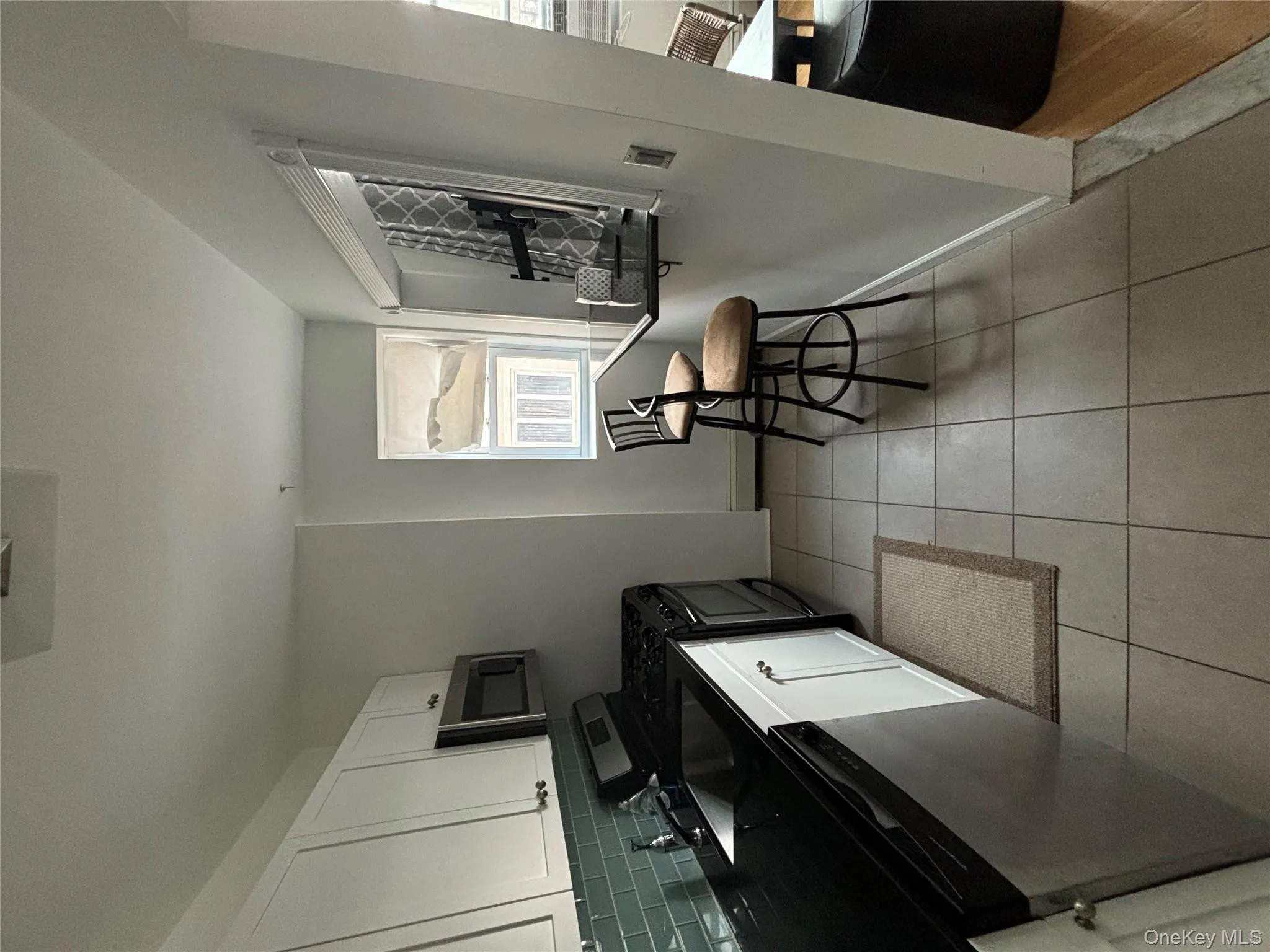 Kitchen featuring stainless steel stove, white cabinets, dishwashing machine, a kitchen bar, and tasteful backsplash Kitchen featuring stainless steel stove, white cabinets, dishwashing machine, a kitchen bar, and tasteful backsplash
