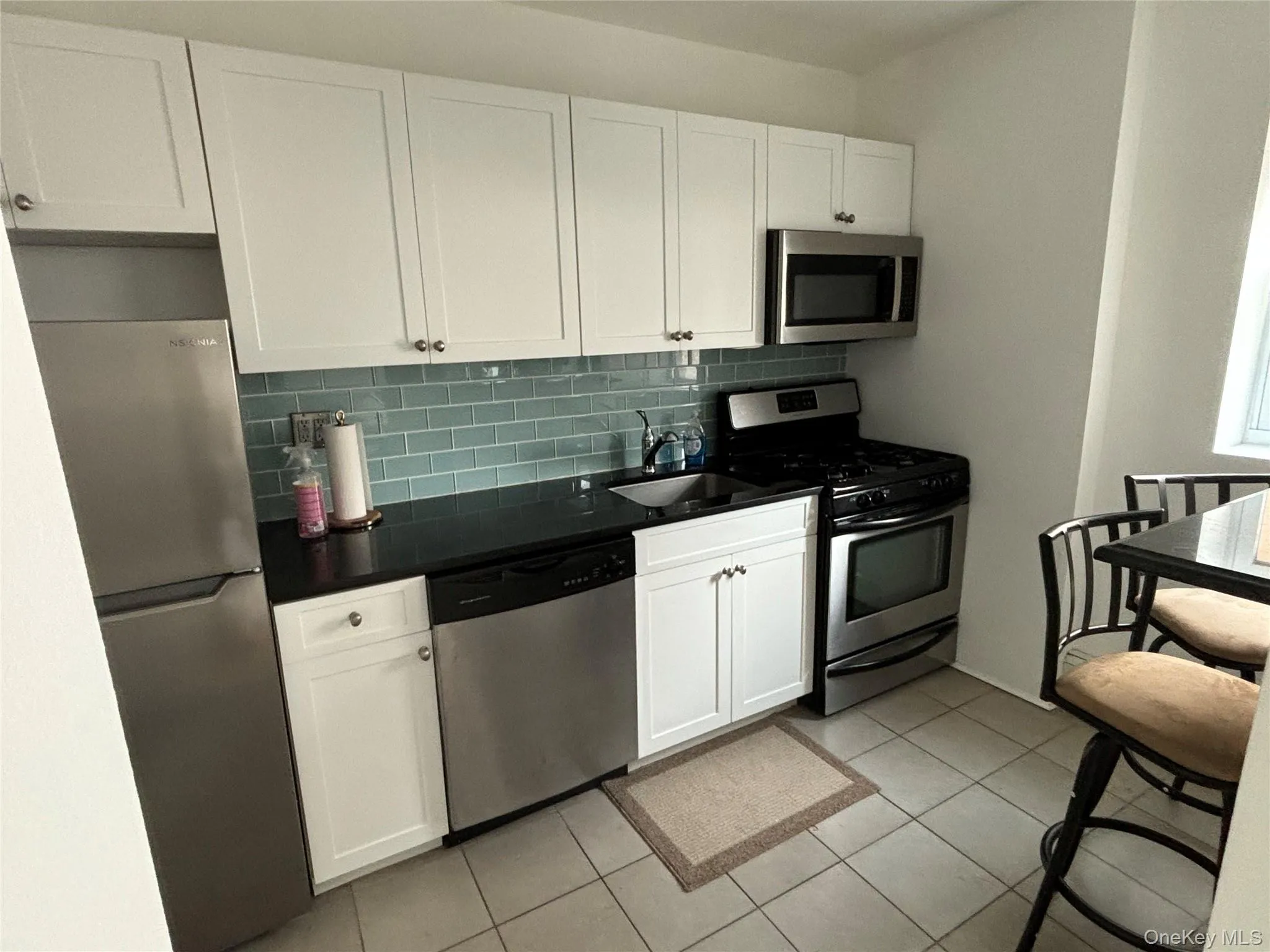 Kitchen with appliances with stainless steel finishes, white cabinetry, and light tile patterned flooring Kitchen with appliances with stainless steel finishes, white cabinetry, and light tile patterned flooring