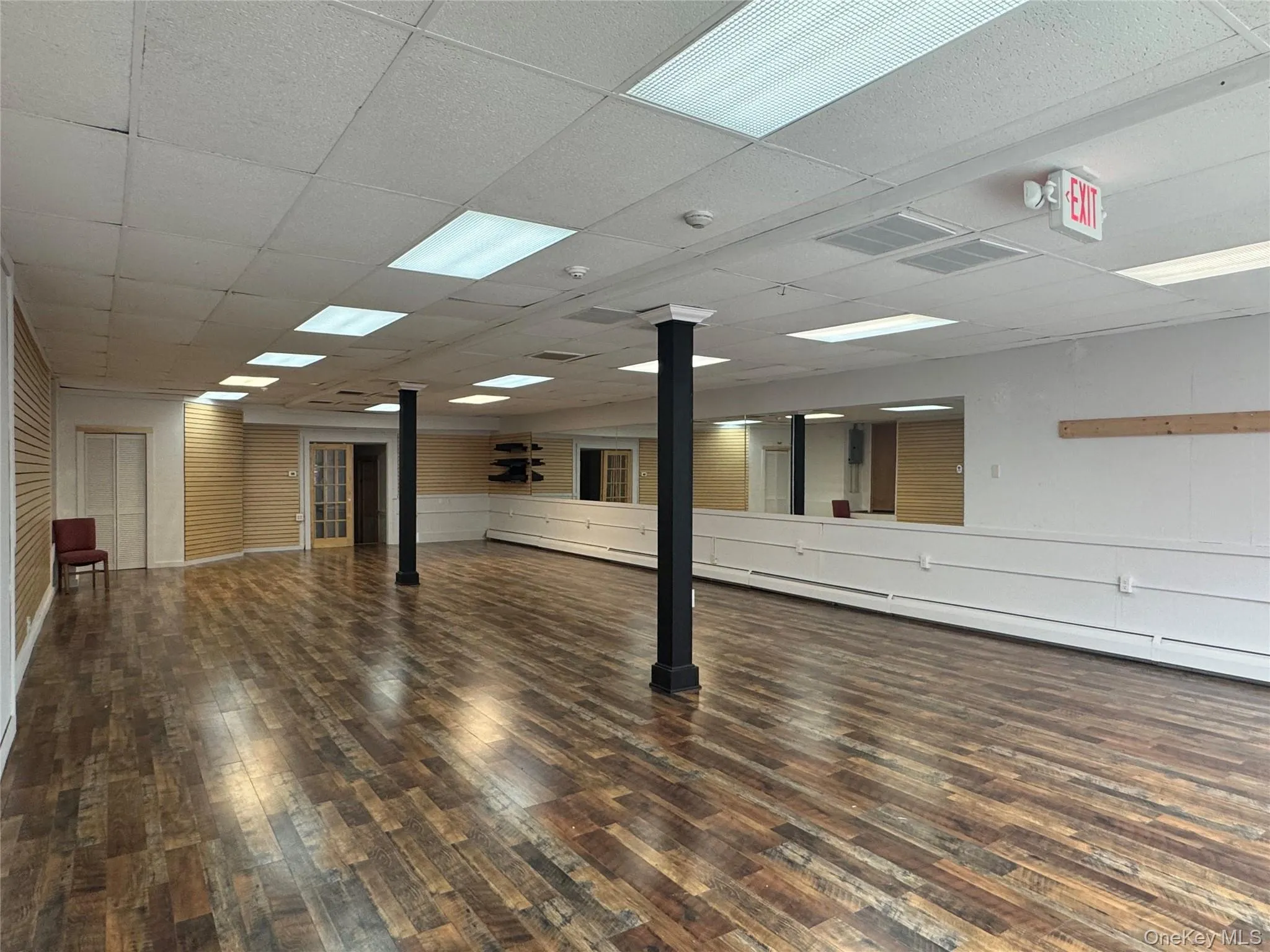 Empty room with hardwood / wood-style floors, decorative columns, a smoke detector, and a paneled ceiling Empty room with hardwood / wood-style floors, decorative columns, a smoke detector, and a paneled ceiling