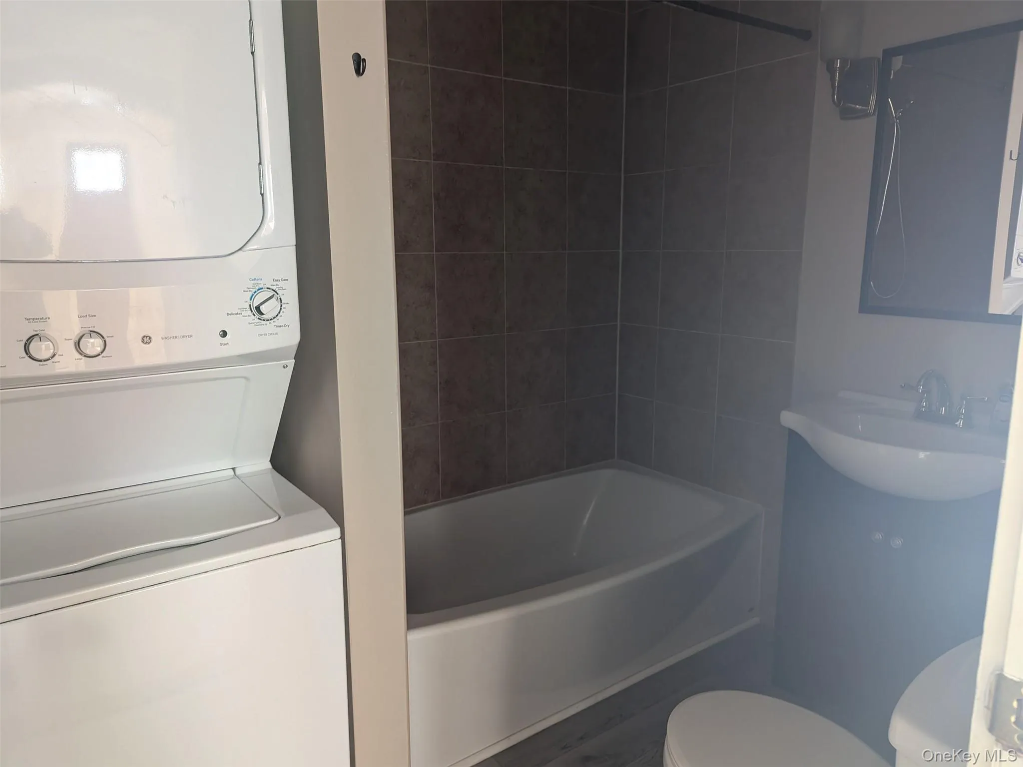 Full bathroom with stacked washer and dryer and shower / bathtub combination Full bathroom with stacked washer and dryer and shower / bathtub combination