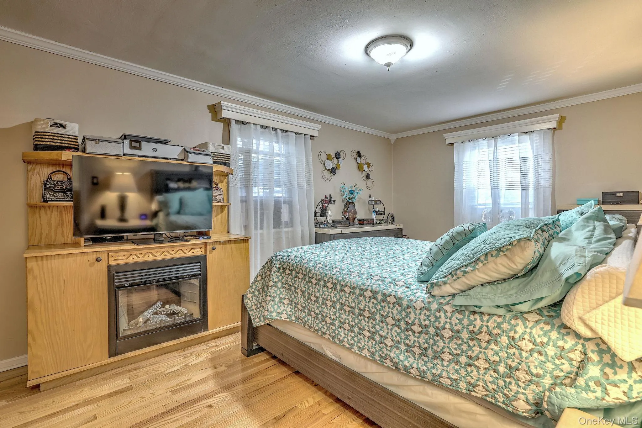 Bedroom with light wood-style flooring, ornamental molding, and a glass covered fireplace Bedroom with light wood-style flooring, ornamental molding, and a glass covered fireplace