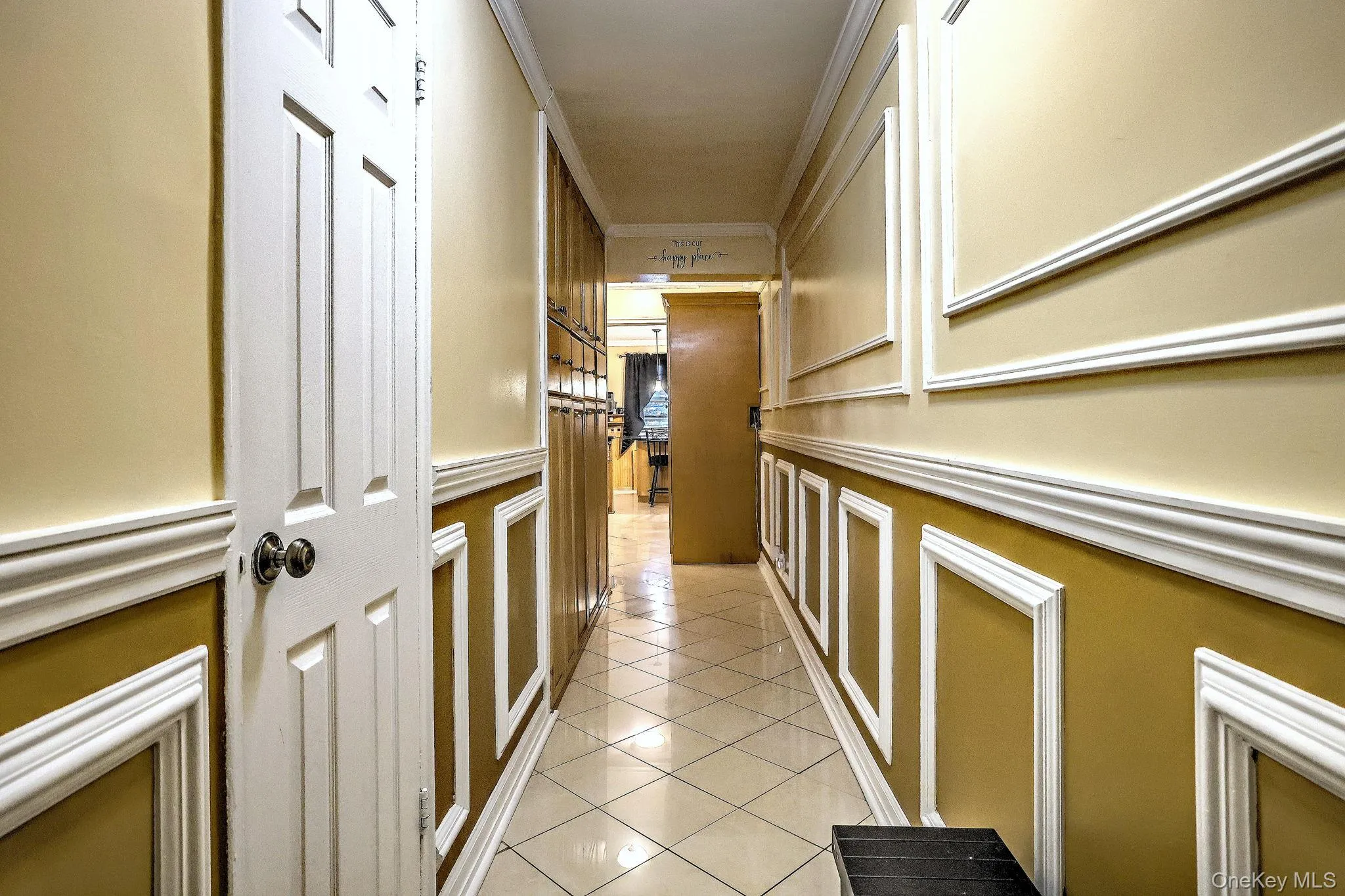 Corridor with crown molding, light tile patterned flooring, and a decorative wall Corridor with crown molding, light tile patterned flooring, and a decorative wall