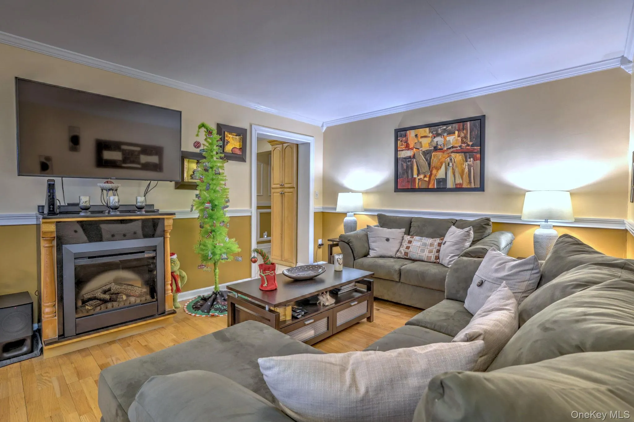Living room featuring light wood-type flooring, ornamental molding, and a glass covered fireplace Living room featuring light wood-type flooring, ornamental molding, and a glass covered fireplace