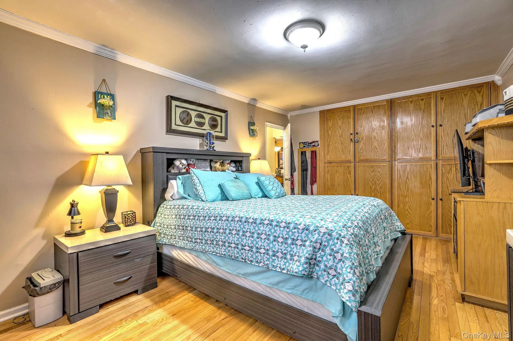 Bedroom with a closet, ornamental molding, and light wood-style flooring Bedroom with a closet, ornamental molding, and light wood-style flooring