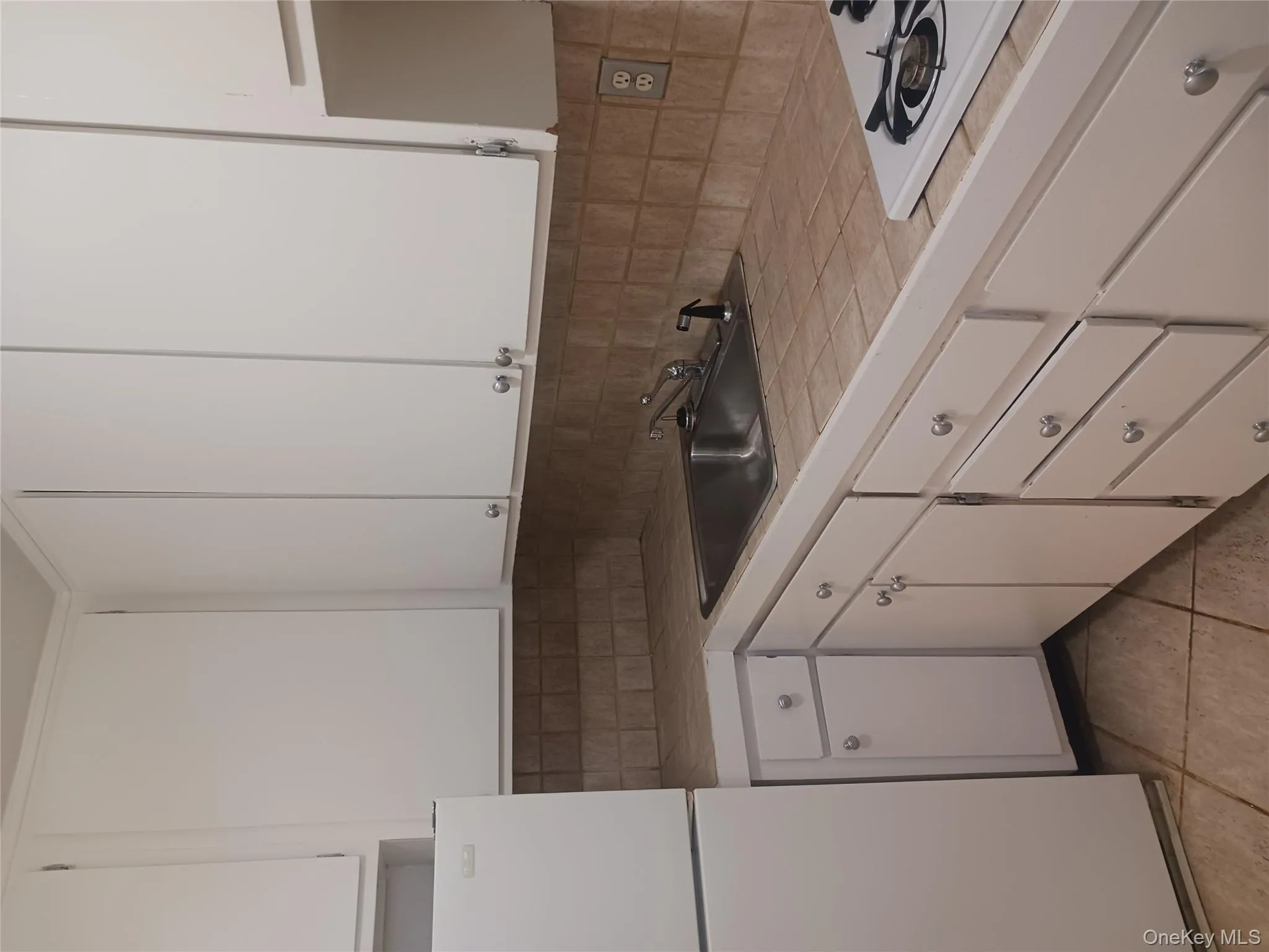 Kitchen with fridge, white cabinets, white cooktop, and light tile patterned flooring Kitchen with fridge, white cabinets, white cooktop, and light tile patterned flooring