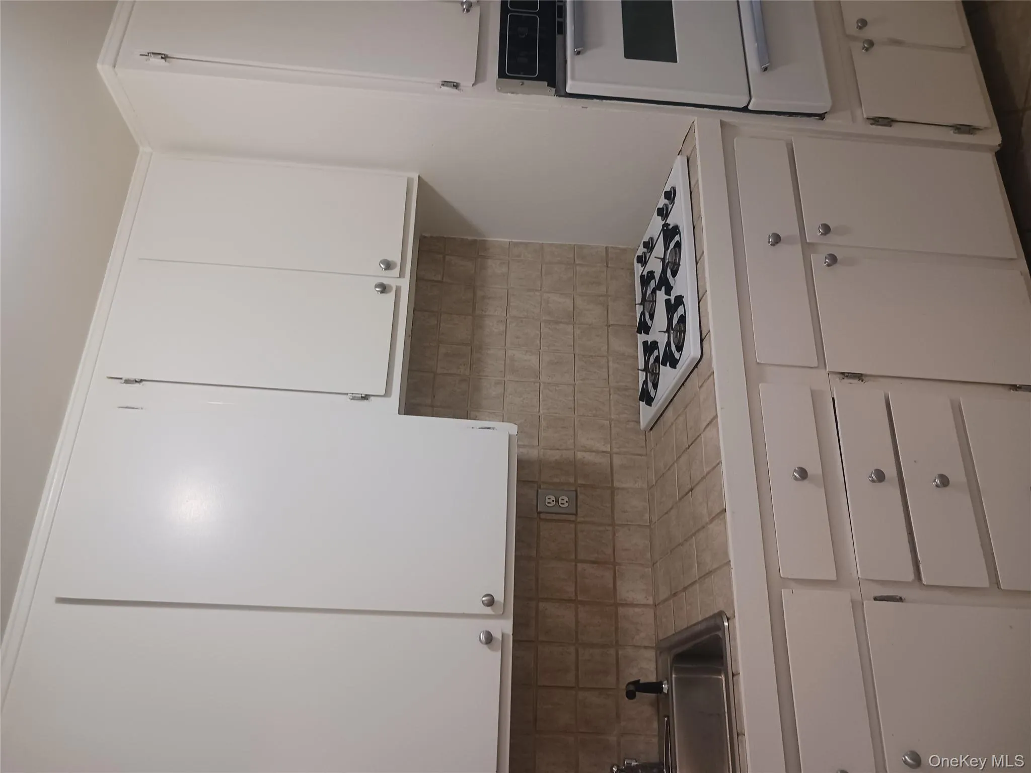 Kitchen featuring white cabinetry, oven, tile counters, a warming drawer, and backsplash Kitchen featuring white cabinetry, oven, tile counters, a warming drawer, and backsplash