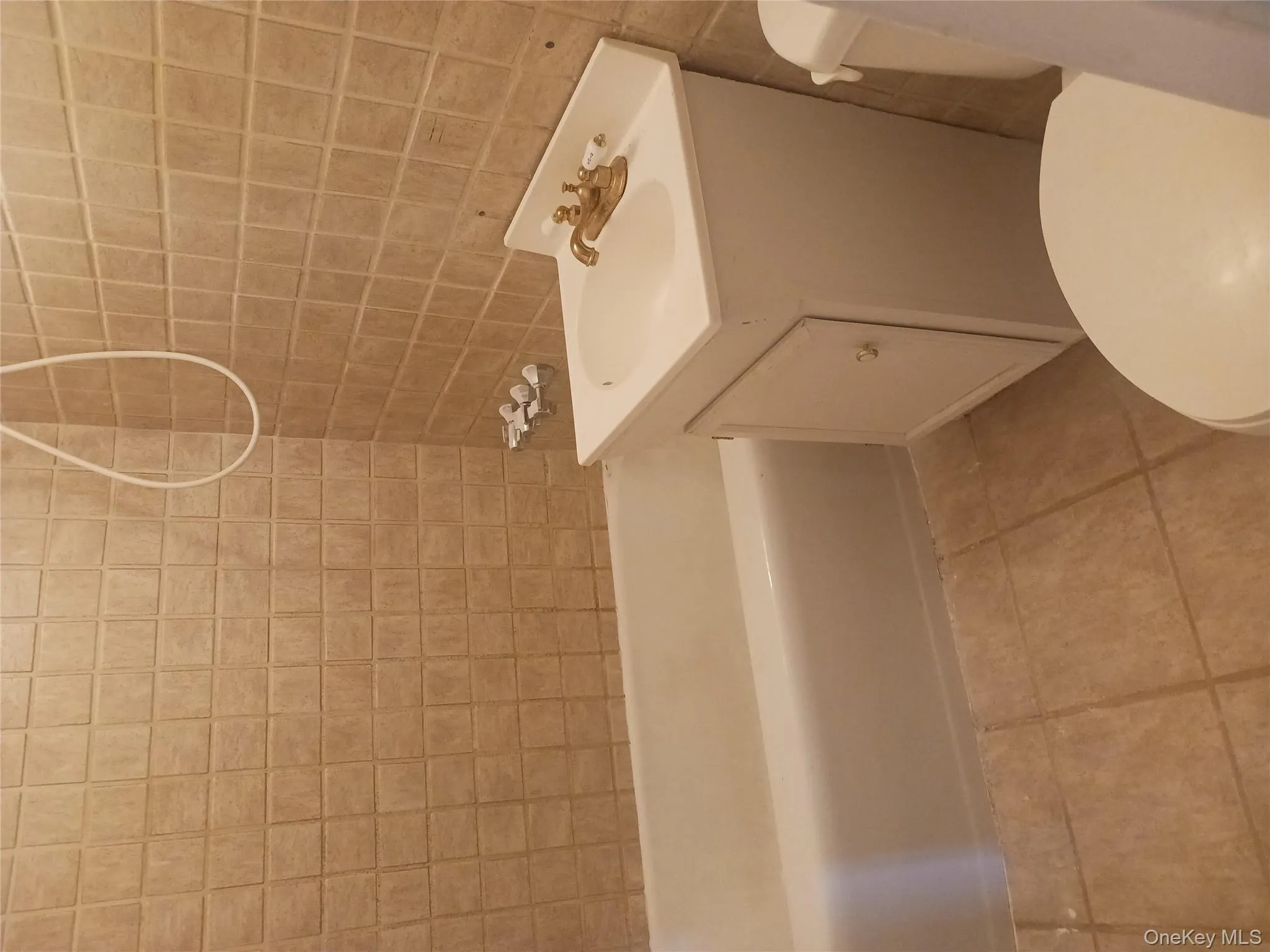 Full bath with vanity, washtub / shower combination, light tile patterned floors, and tile walls Full bath with vanity, washtub / shower combination, light tile patterned floors, and tile walls