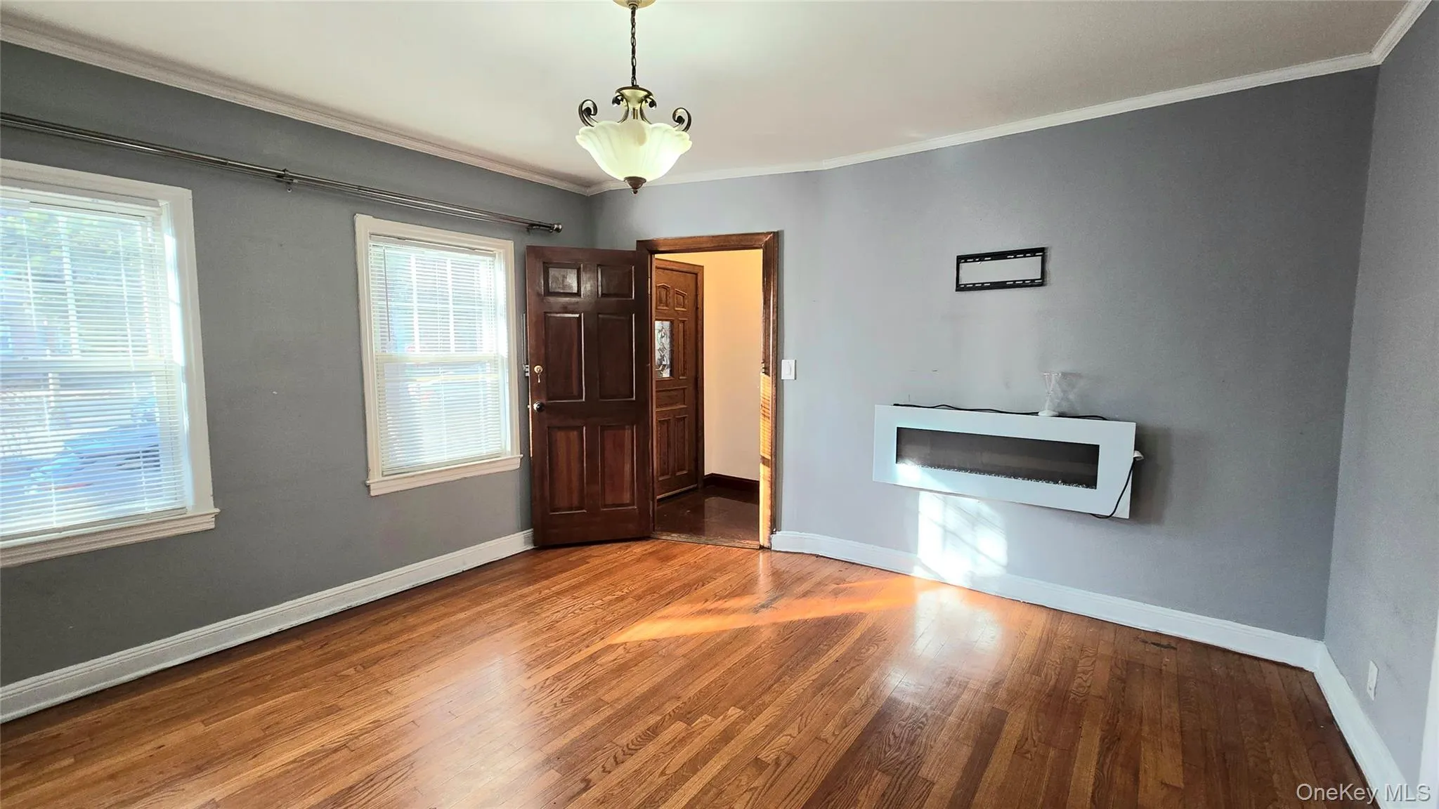 Unfurnished living room featuring ornamental molding and wood finished floors Unfurnished living room featuring ornamental molding and wood finished floors