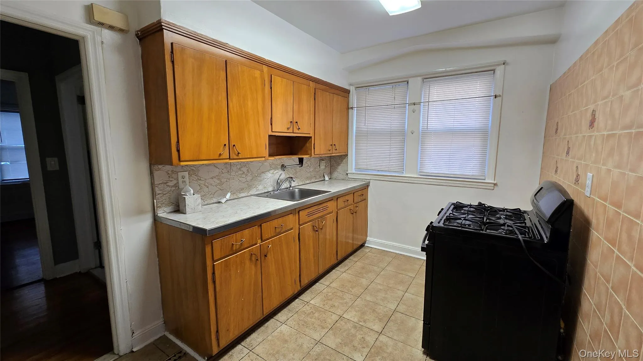 Kitchen featuring black gas stove, brown cabinetry, light countertops, and light tile patterned floors Kitchen featuring black gas stove, brown cabinetry, light countertops, and light tile patterned floors