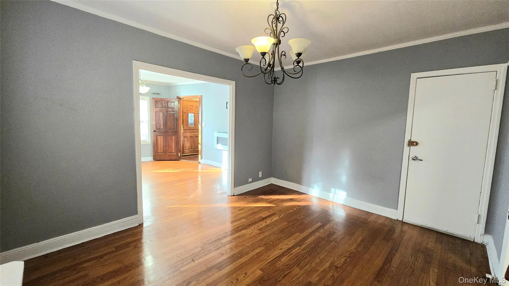 Unfurnished room with ornamental molding, dark wood-type flooring, and a chandelier Unfurnished room with ornamental molding, dark wood-type flooring, and a chandelier