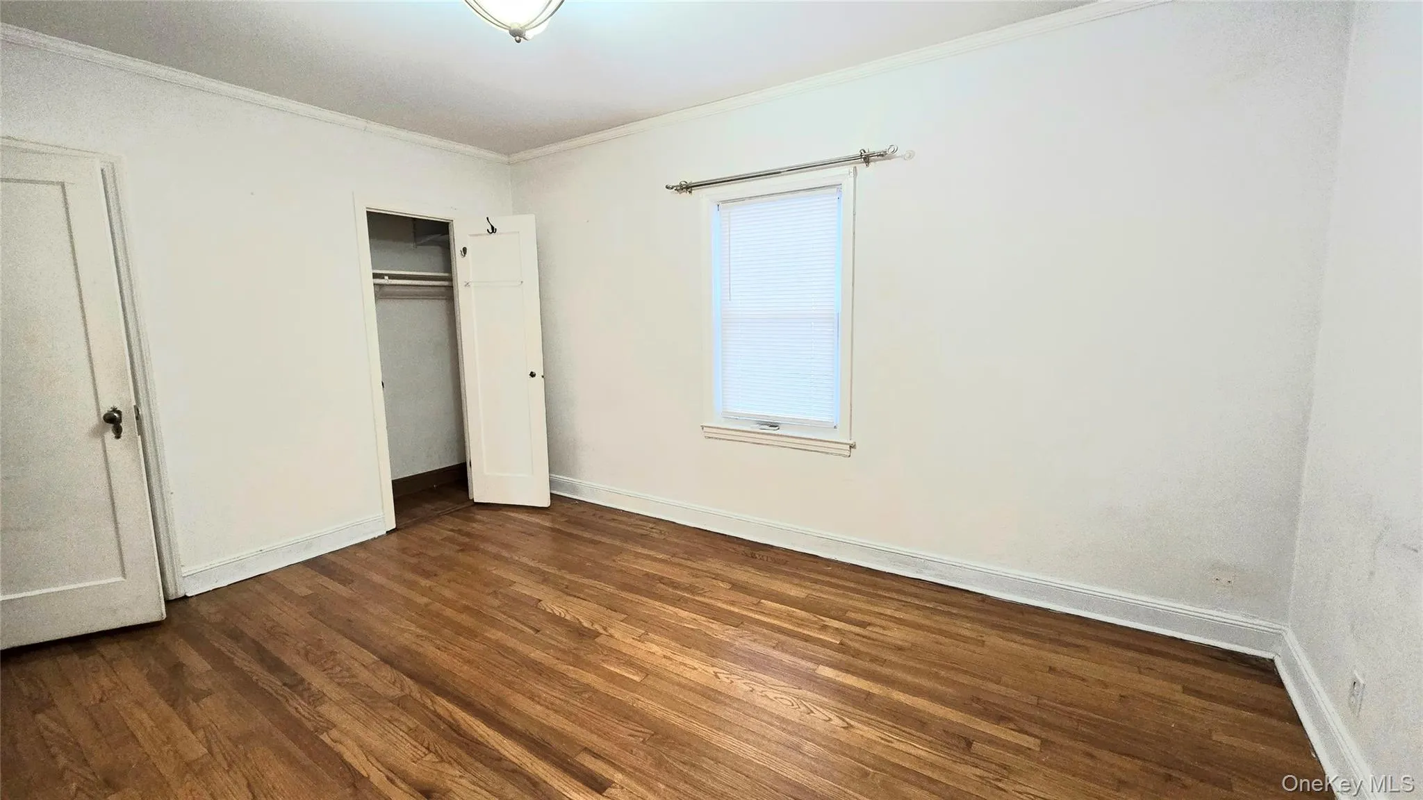 Unfurnished bedroom featuring crown molding, dark wood-type flooring, and a closet Unfurnished bedroom featuring crown molding, dark wood-type flooring, and a closet
