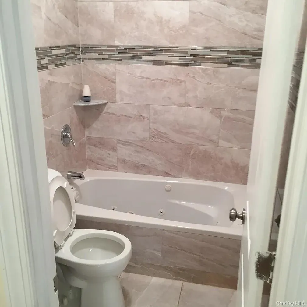 Full bathroom featuring a combined bath / shower with jetted tub and tile patterned flooring Full bathroom featuring a combined bath / shower with jetted tub and tile patterned flooring