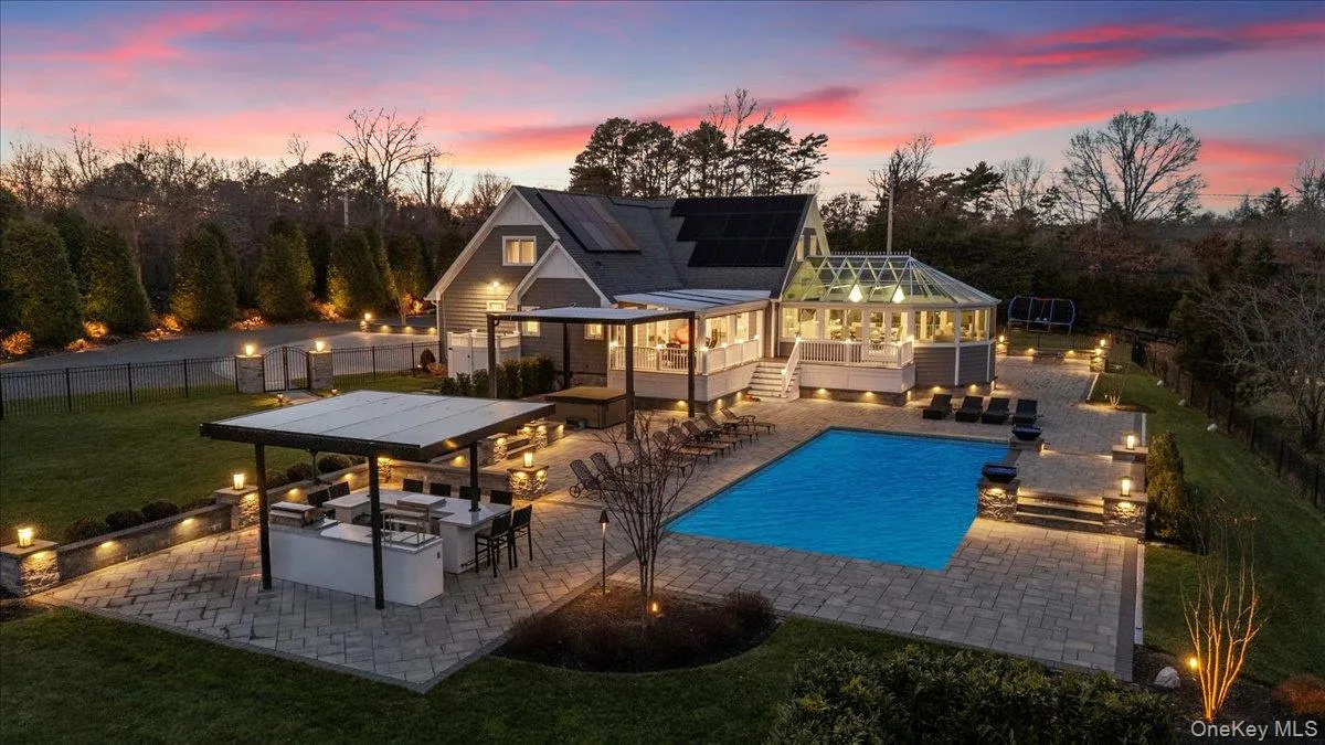 View of pool featuring a patio, a fenced backyard, exterior kitchen, and a sunroom View of pool featuring a patio, a fenced backyard, exterior kitchen, and a sunroom