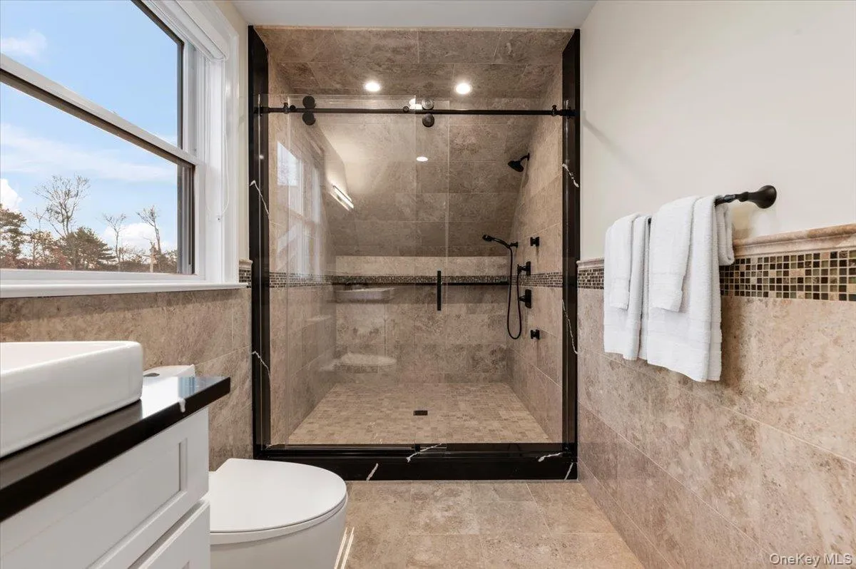 Bathroom featuring tile walls, a stall shower, vanity, and wainscoting Bathroom featuring tile walls, a stall shower, vanity, and wainscoting
