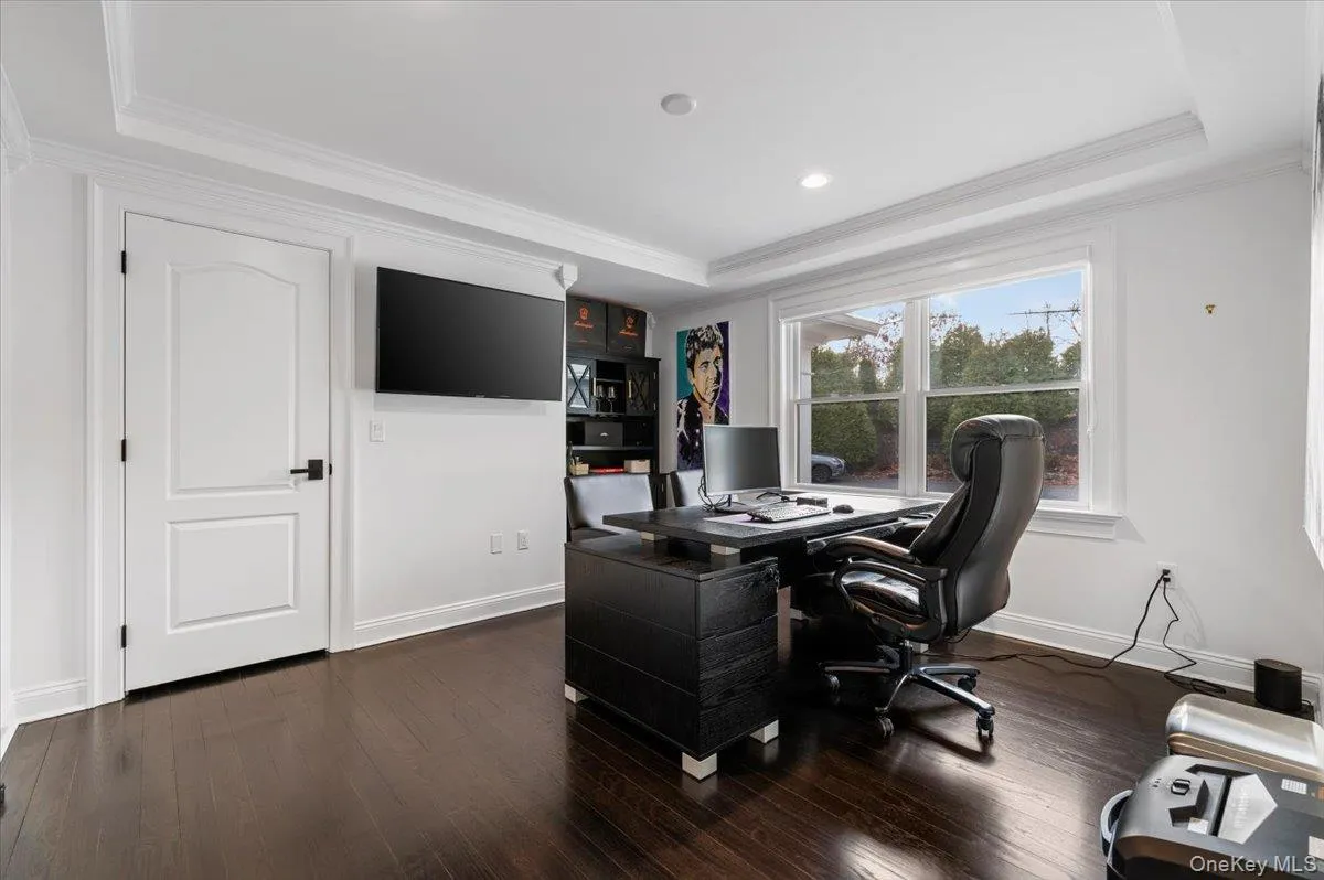 Office space featuring ornamental molding, dark wood-style floors, and a raised ceiling Office space featuring ornamental molding, dark wood-style floors, and a raised ceiling