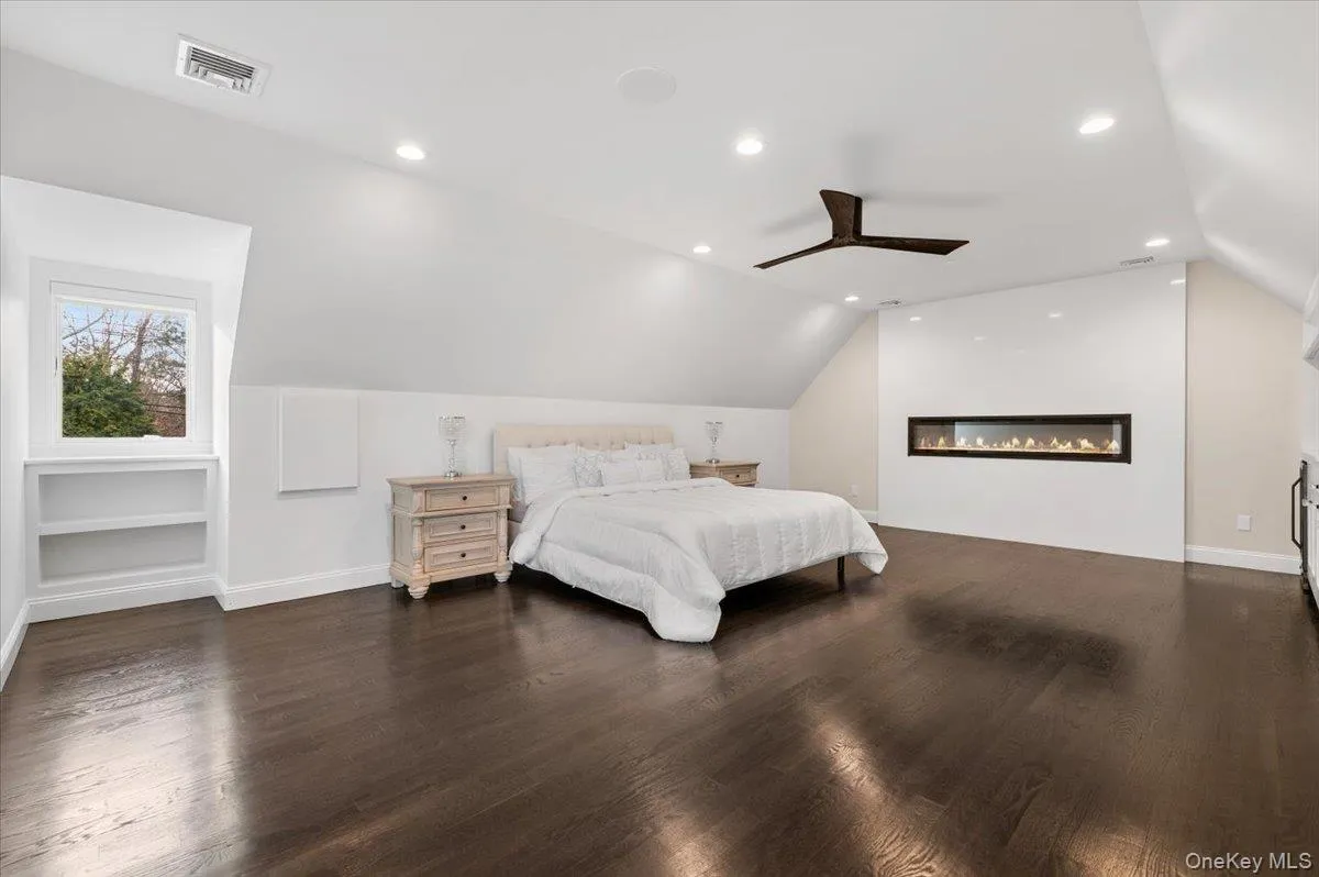 Bedroom featuring vaulted ceiling, ceiling fan, dark wood-style floors, recessed lighting, and a glass covered fireplace Bedroom featuring vaulted ceiling, ceiling fan, dark wood-style floors, recessed lighting, and a glass covered fireplace