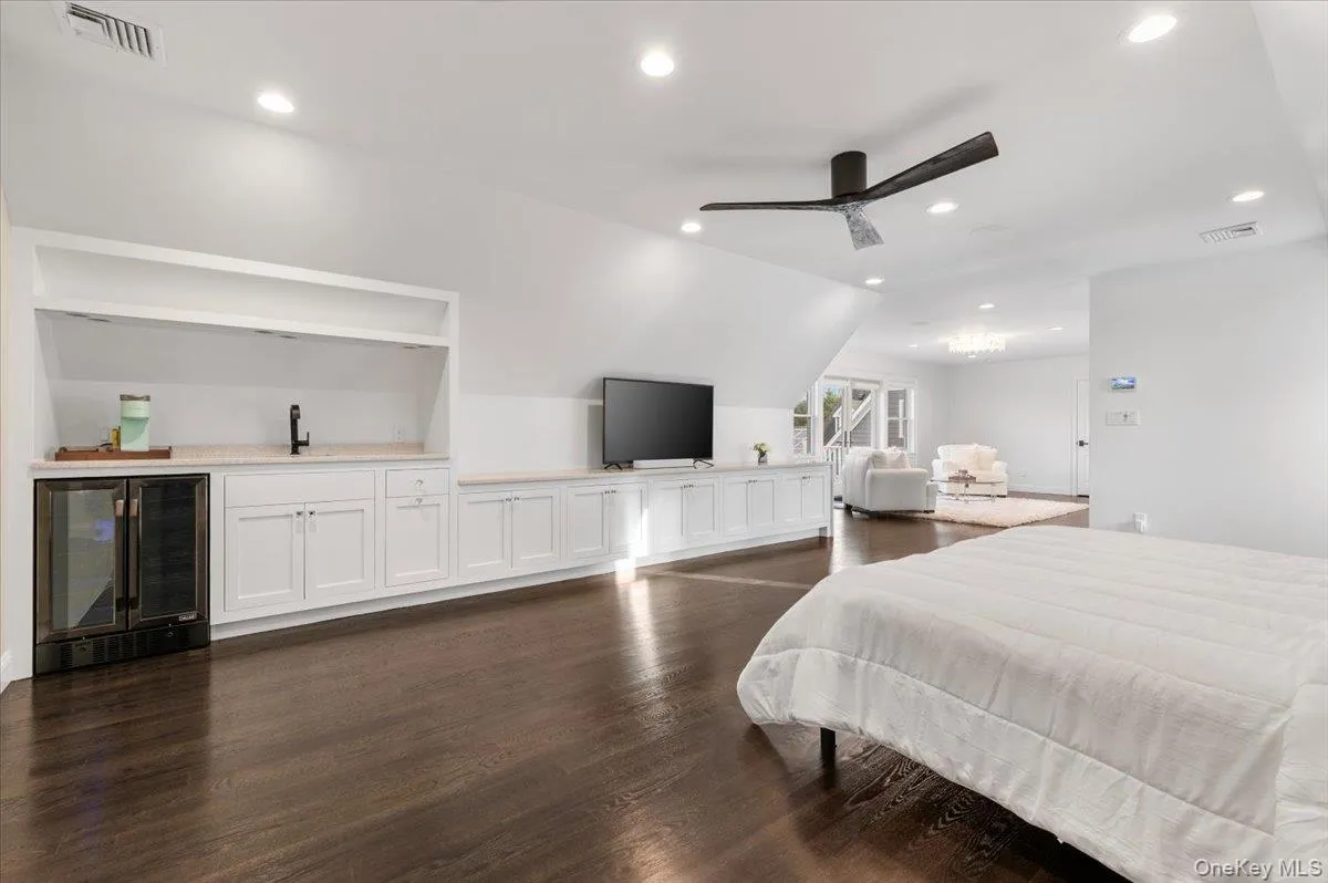Bedroom featuring wine cooler, lofted ceiling, dark wood-style flooring, recessed lighting, and bar with sink Bedroom featuring wine cooler, lofted ceiling, dark wood-style flooring, recessed lighting, and bar with sink
