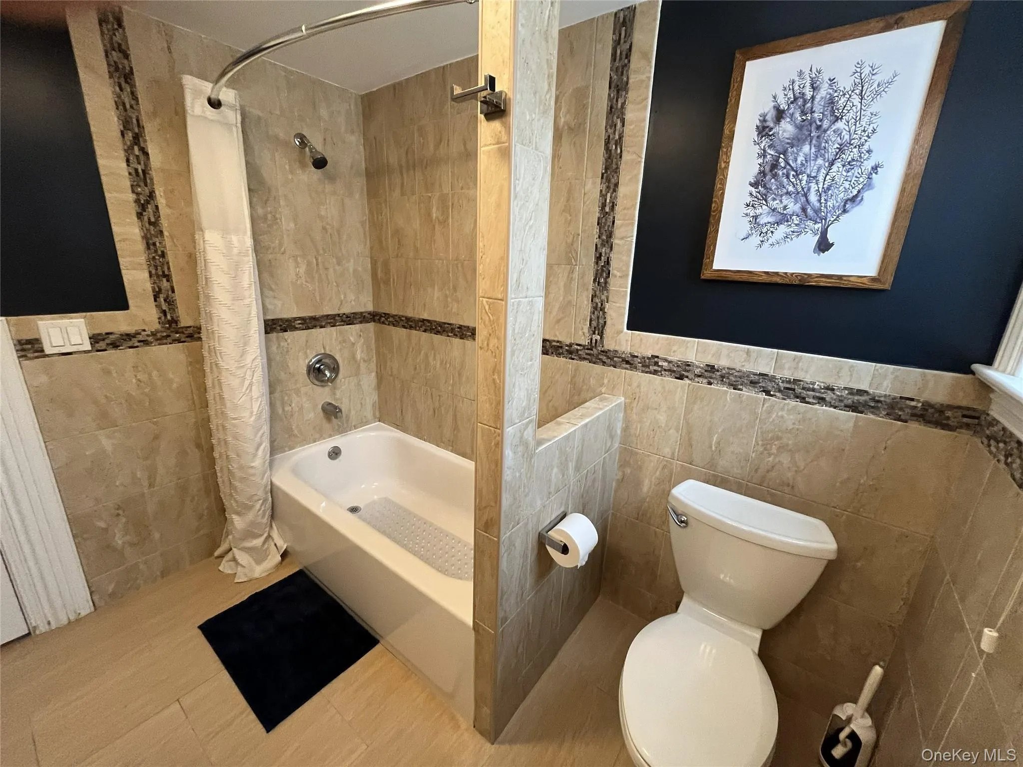 Bathroom featuring tile walls and shower / tub combo with curtain Bathroom featuring tile walls and shower / tub combo with curtain