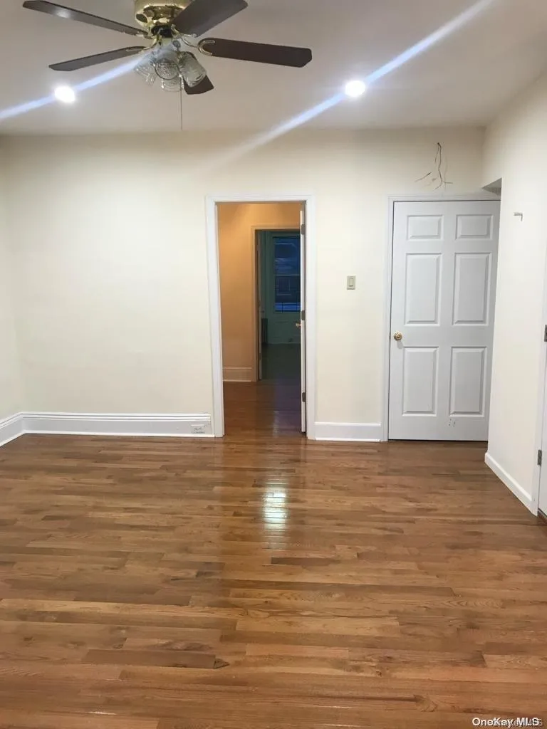Empty room with dark wood finished floors and a ceiling fan Empty room with dark wood finished floors and a ceiling fan