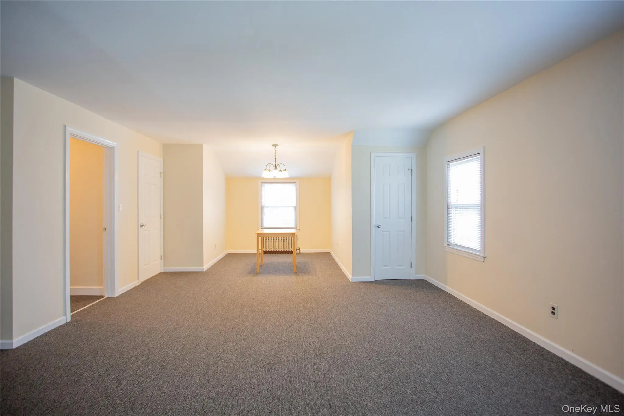 Spare room featuring a chandelier, radiator, and dark colored carpet Spare room featuring a chandelier, radiator, and dark colored carpet