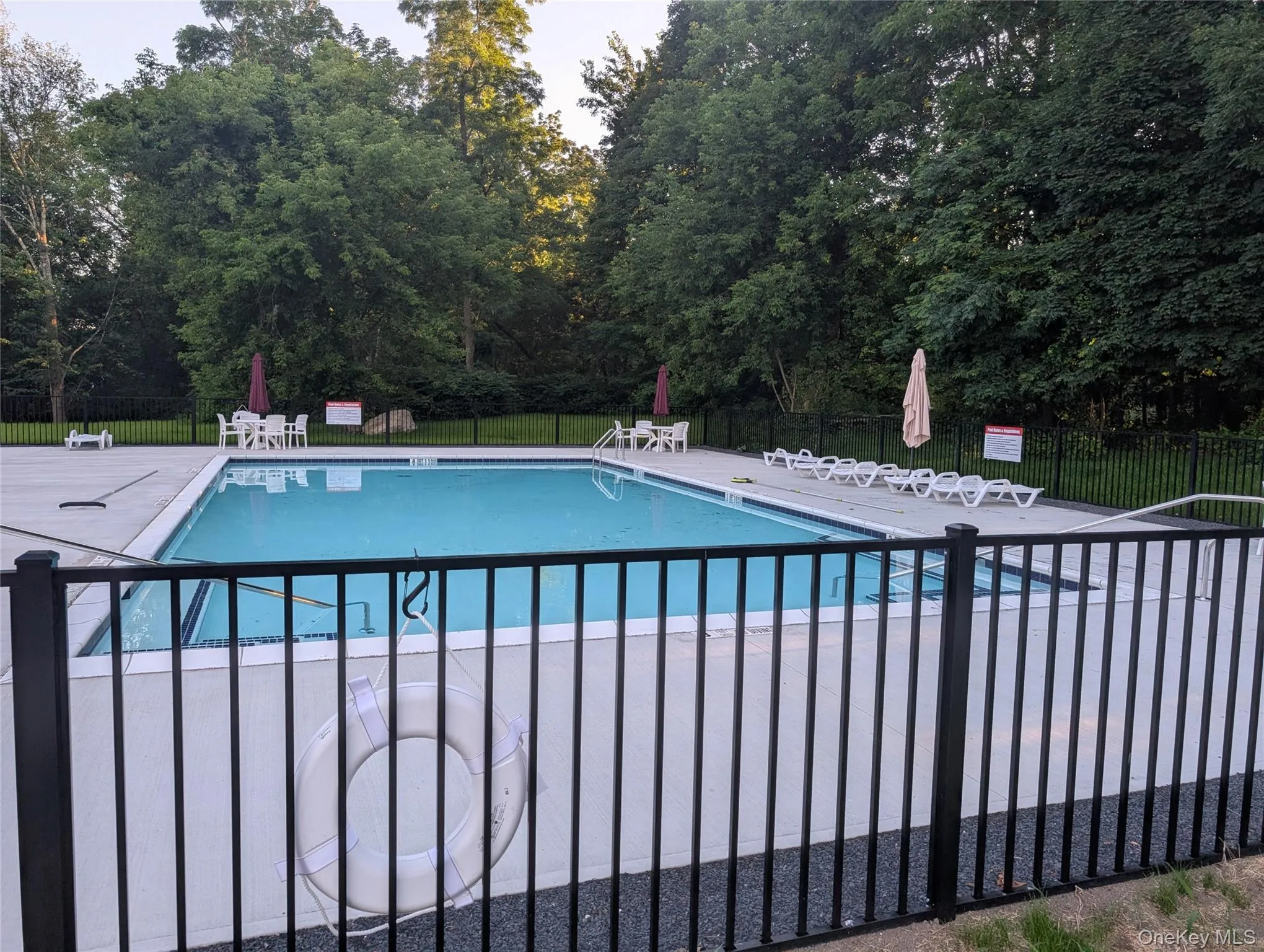Brand new community pool featuring a patio area and view of wooded area Brand new community pool featuring a patio area and view of wooded area