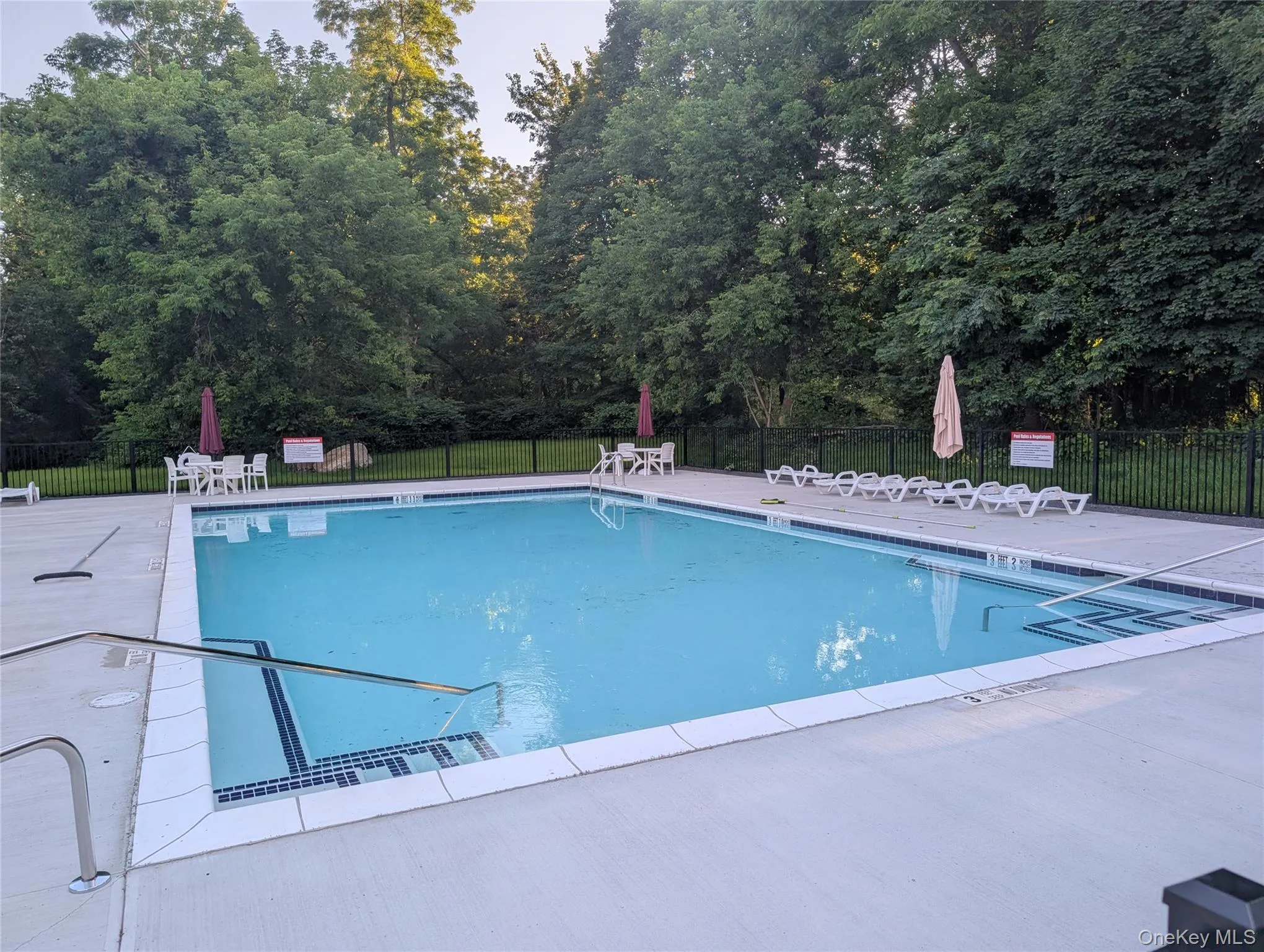 Community pool featuring a patio area and view of scattered trees Community pool featuring a patio area and view of scattered trees