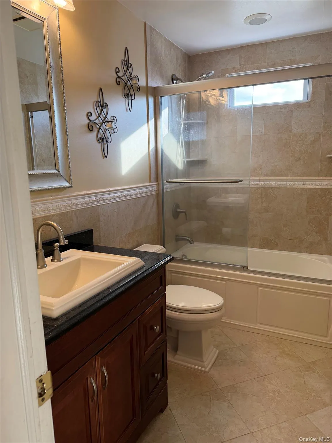 Full bath featuring vanity, enclosed tub / shower combo, and tile walls Full bath featuring vanity, enclosed tub / shower combo, and tile walls