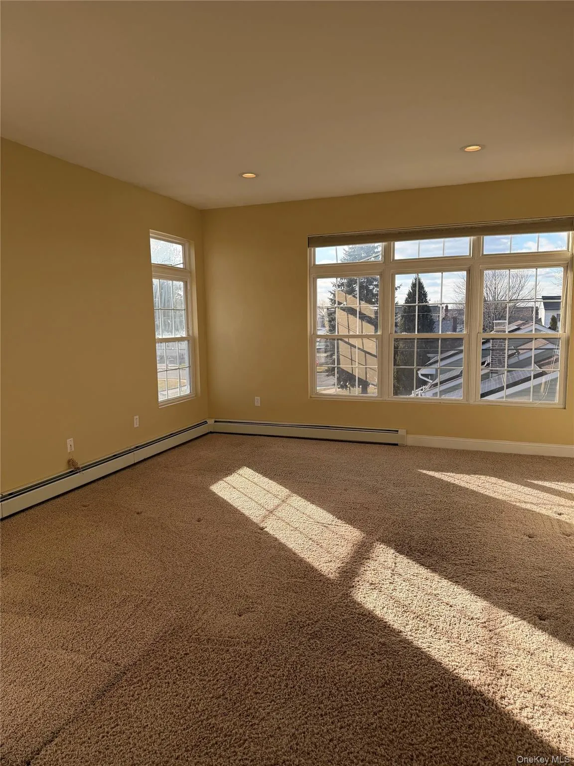 Empty room with carpet flooring, a baseboard radiator, and recessed lighting Empty room with carpet flooring, a baseboard radiator, and recessed lighting