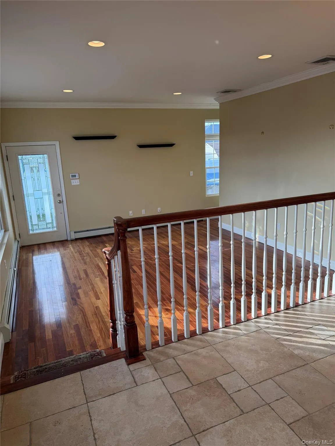 Hall featuring crown molding, a baseboard heating unit, recessed lighting, and wood finished floors Hall featuring crown molding, a baseboard heating unit, recessed lighting, and wood finished floors