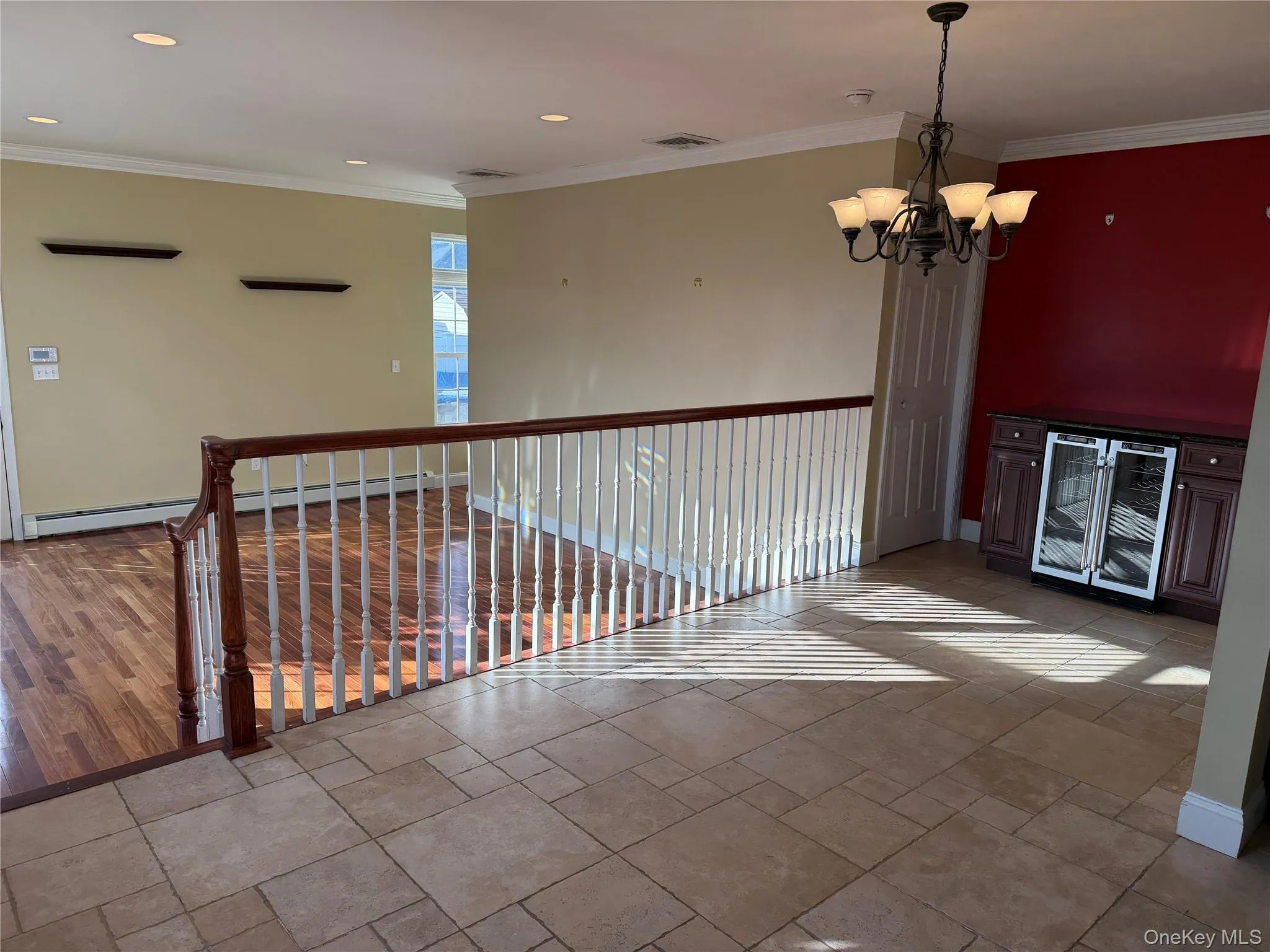 Spare room featuring wine cooler, a chandelier, ornamental molding, recessed lighting, and baseboard heating Spare room featuring wine cooler, a chandelier, ornamental molding, recessed lighting, and baseboard heating