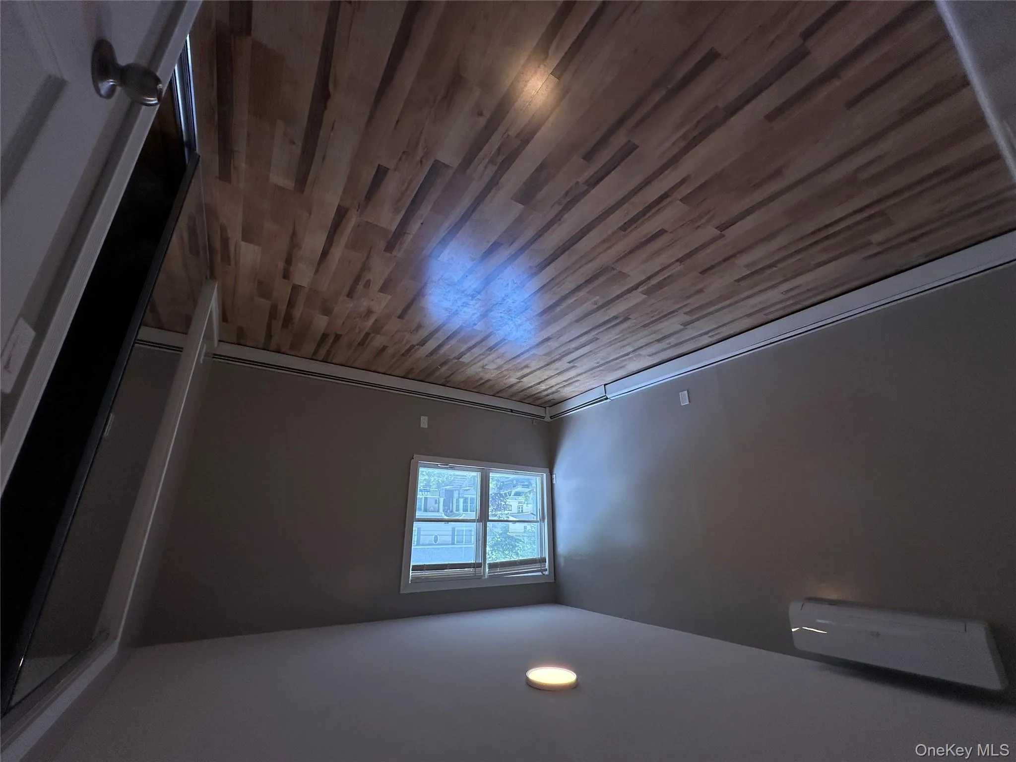 Spare room with a baseboard heating unit, wood finished floors, an AC wall unit, and baseboard heating Spare room with a baseboard heating unit, wood finished floors, an AC wall unit, and baseboard heating