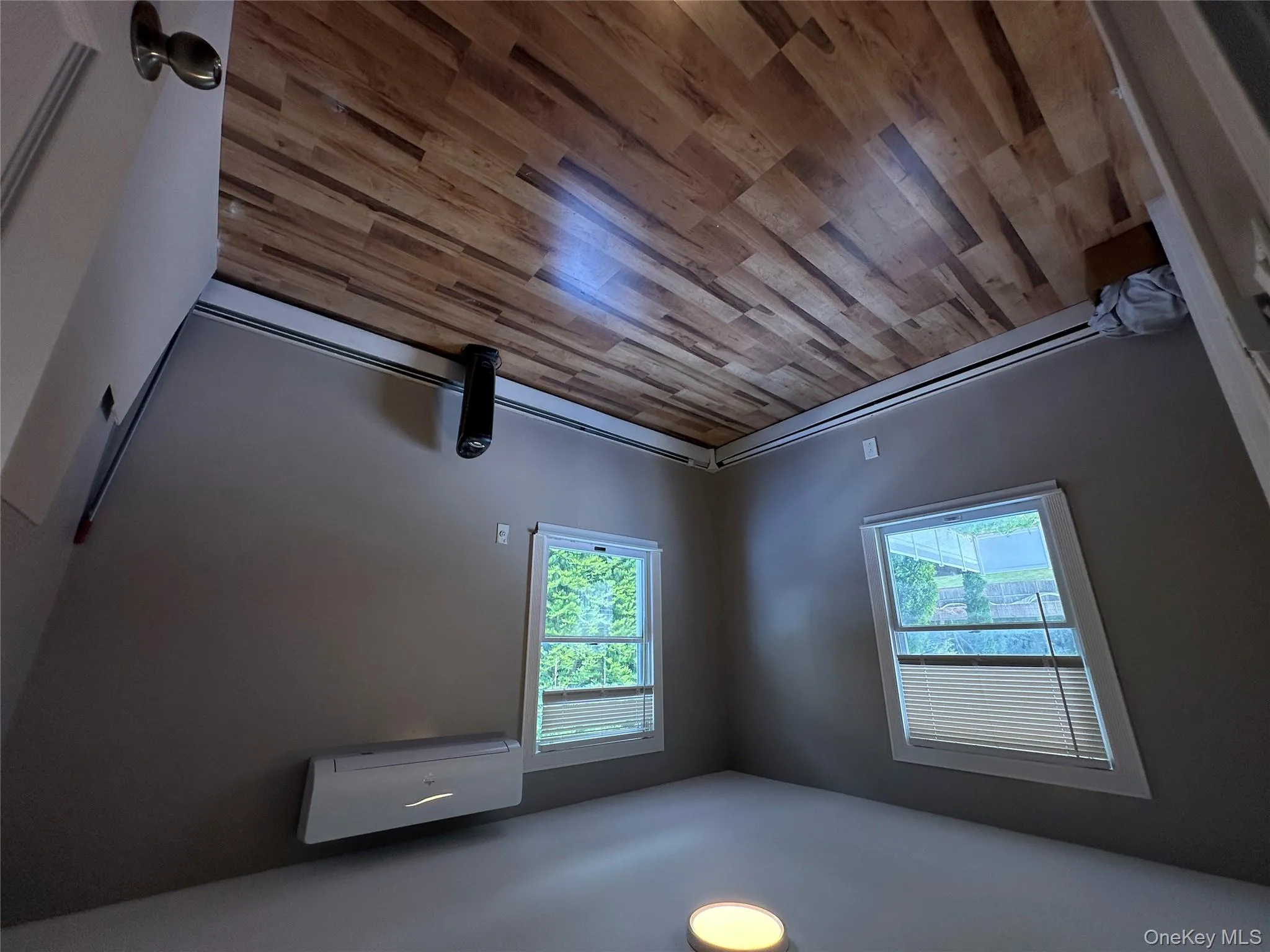 Spare room with light wood-style flooring, baseboard heating, and a wall unit AC Spare room with light wood-style flooring, baseboard heating, and a wall unit AC