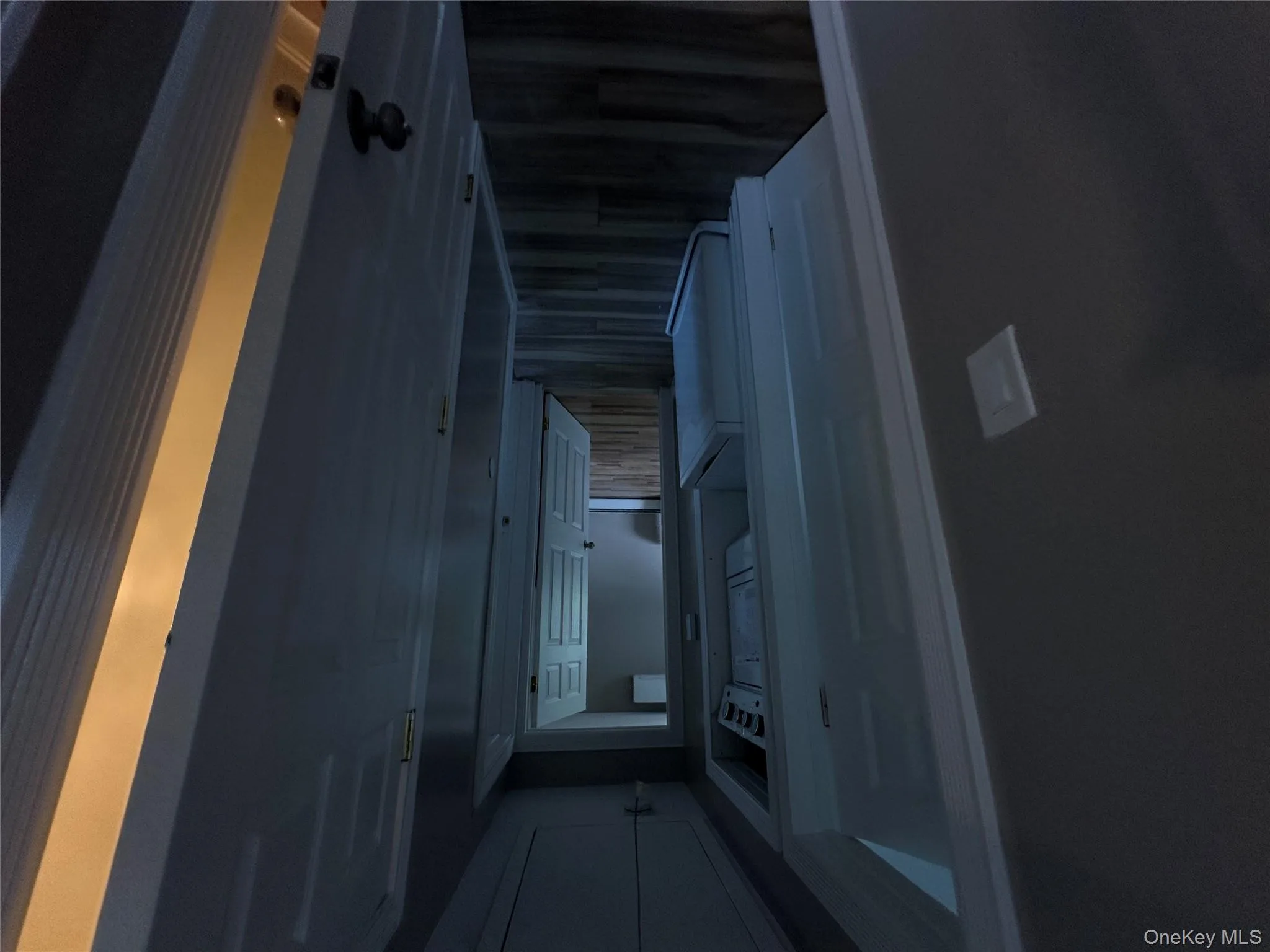 Corridor with attic access, wood finished floors, and stacked washing machine and dryer Corridor with attic access, wood finished floors, and stacked washing machine and dryer