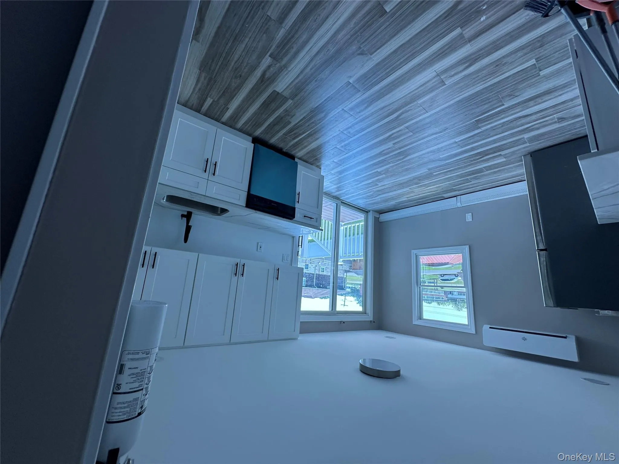 Kitchen featuring fridge, white cabinetry, dishwashing machine, and dark wood-style flooring Kitchen featuring fridge, white cabinetry, dishwashing machine, and dark wood-style flooring