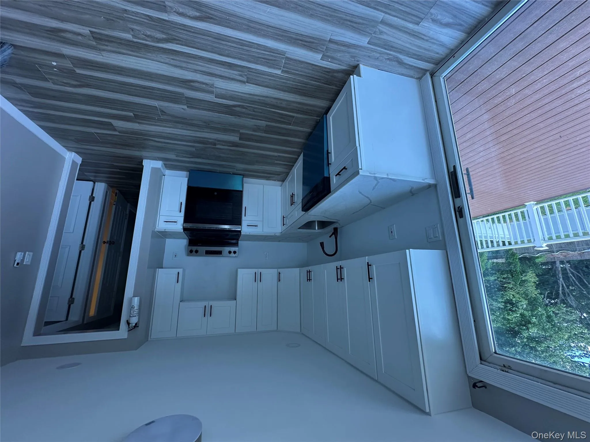 Kitchen featuring white cabinetry, range, light stone countertops, dishwashing machine, and wood tiled floors Kitchen featuring white cabinetry, range, light stone countertops, dishwashing machine, and wood tiled floors