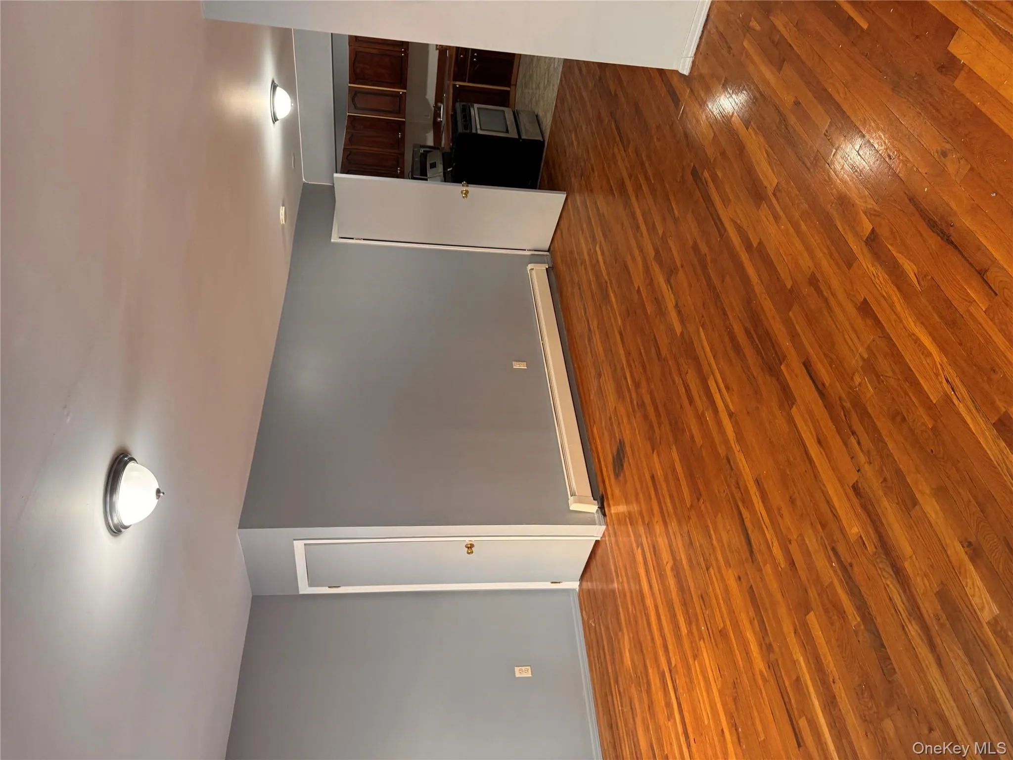 Unfurnished living room with a baseboard heating unit and dark wood-type flooring Unfurnished living room with a baseboard heating unit and dark wood-type flooring