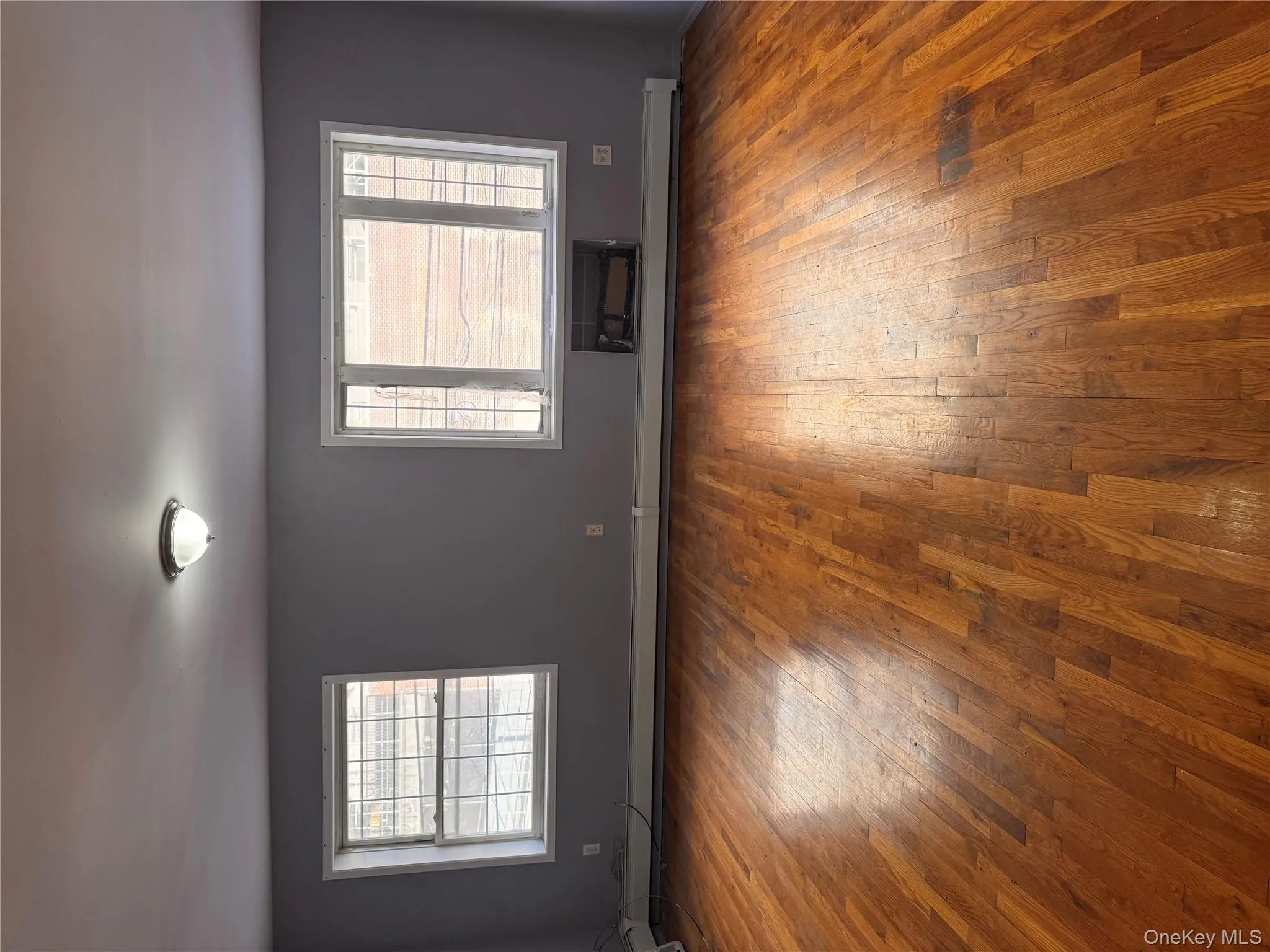 Spare room with plenty of natural light, wood-type flooring, and a baseboard heating unit Spare room with plenty of natural light, wood-type flooring, and a baseboard heating unit