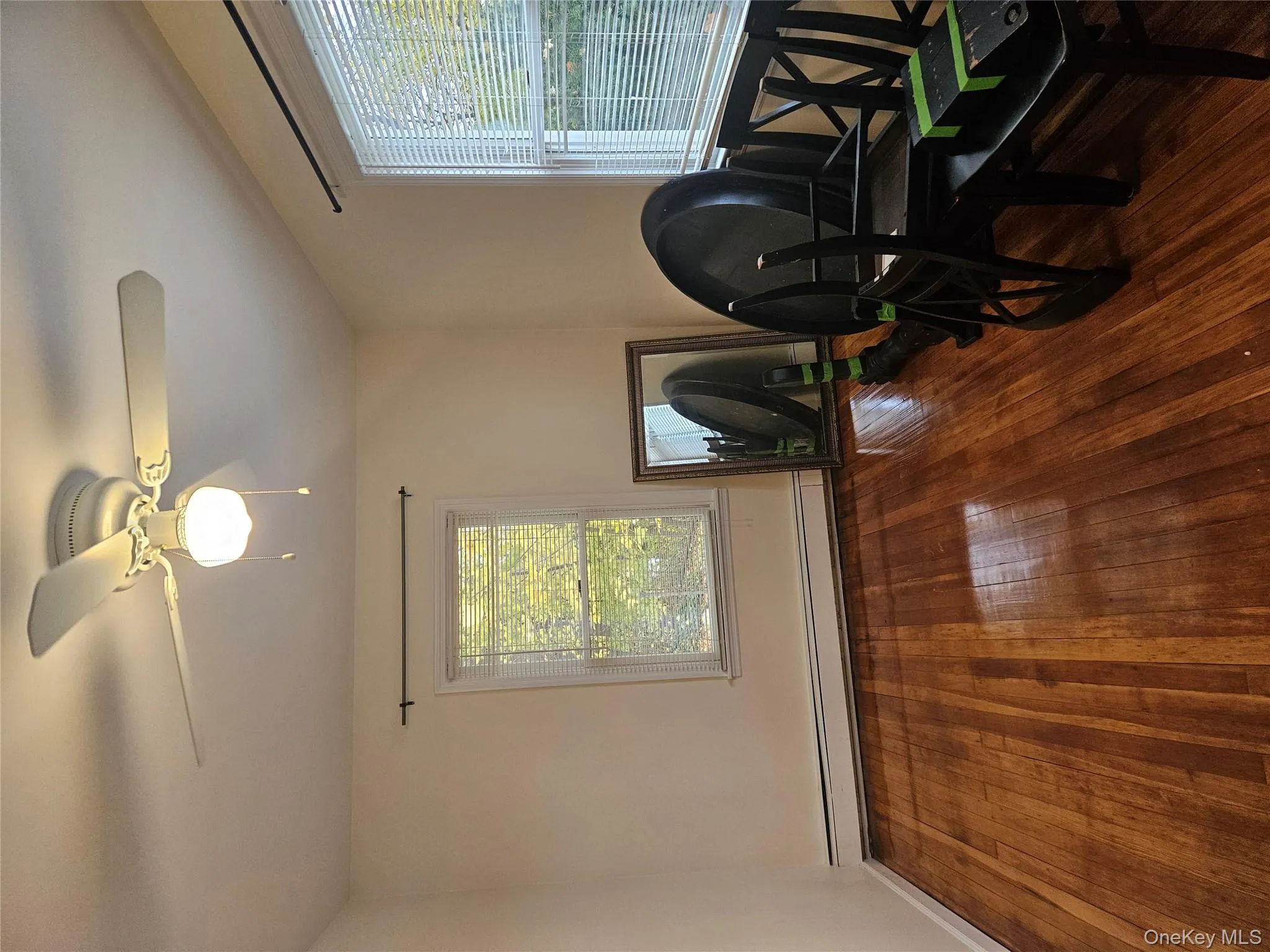 Living area featuring a baseboard radiator, a ceiling fan, and wood-type flooring Living area featuring a baseboard radiator, a ceiling fan, and wood-type flooring