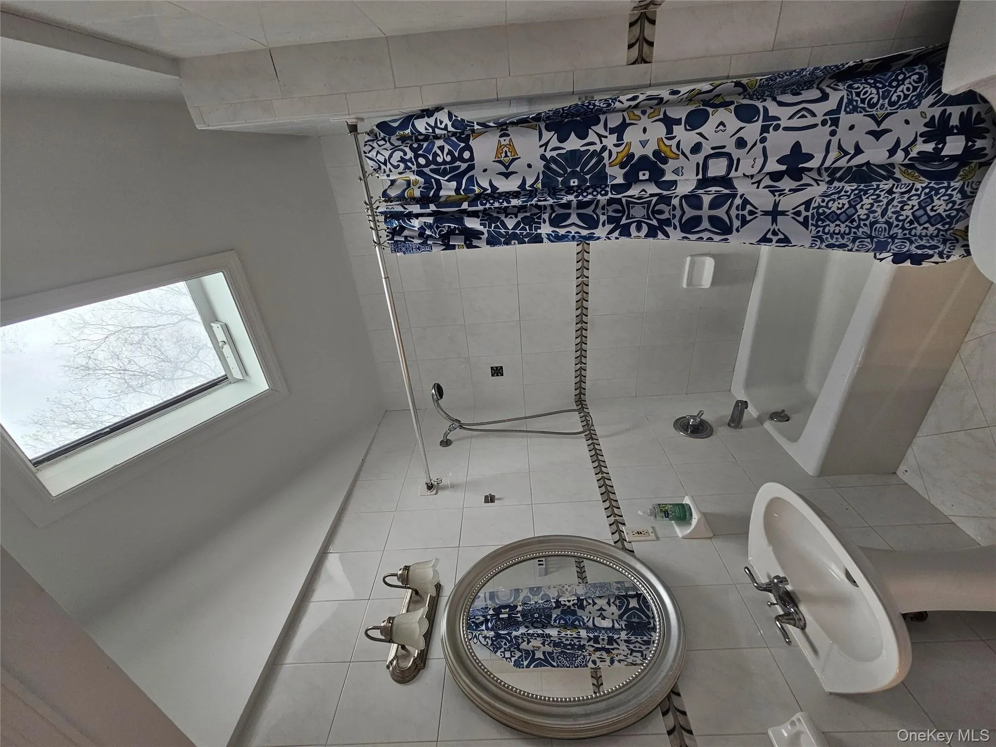 Full bathroom featuring lofted ceiling, tile walls, shower / bath combination with curtain, and a skylight Full bathroom featuring lofted ceiling, tile walls, shower / bath combination with curtain, and a skylight