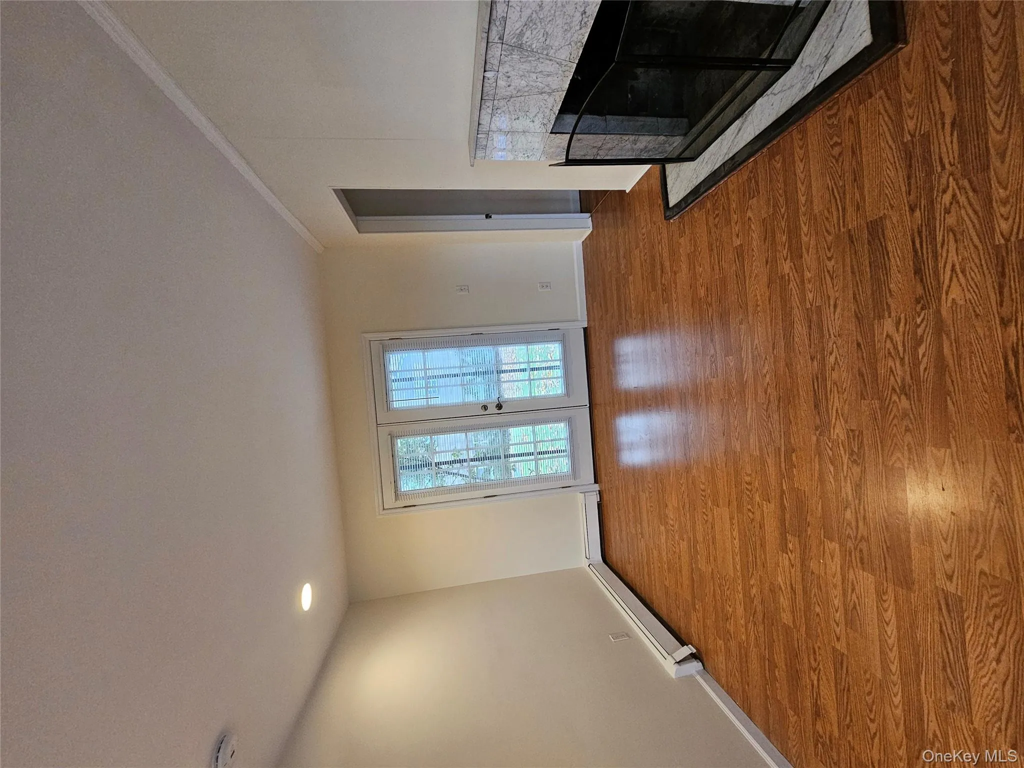Unfurnished living room featuring a fireplace, wood finished floors, and a baseboard heating unit Unfurnished living room featuring a fireplace, wood finished floors, and a baseboard heating unit