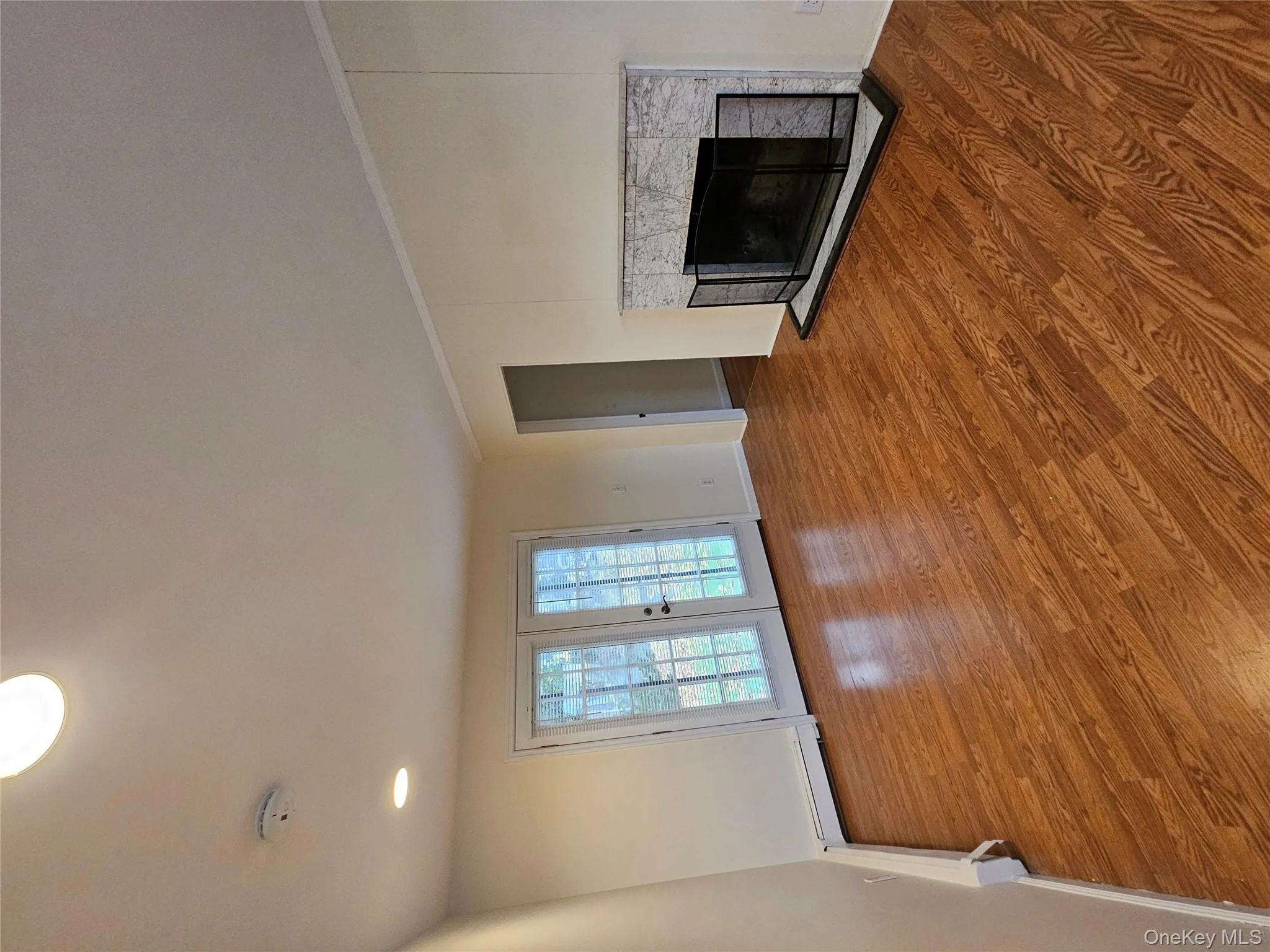 Unfurnished living room with a fireplace, wood finished floors, french doors, and a baseboard radiator Unfurnished living room with a fireplace, wood finished floors, french doors, and a baseboard radiator