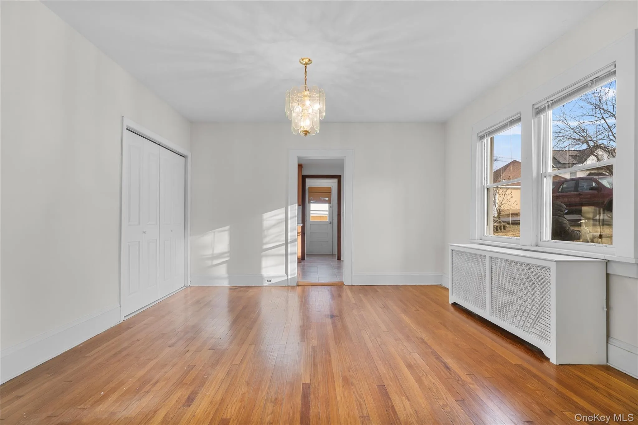 Unfurnished dining area featuring a chandelier, radiator, light wood-type flooring, and plenty of natural light Unfurnished dining area featuring a chandelier, radiator, light wood-type flooring, and plenty of natural light