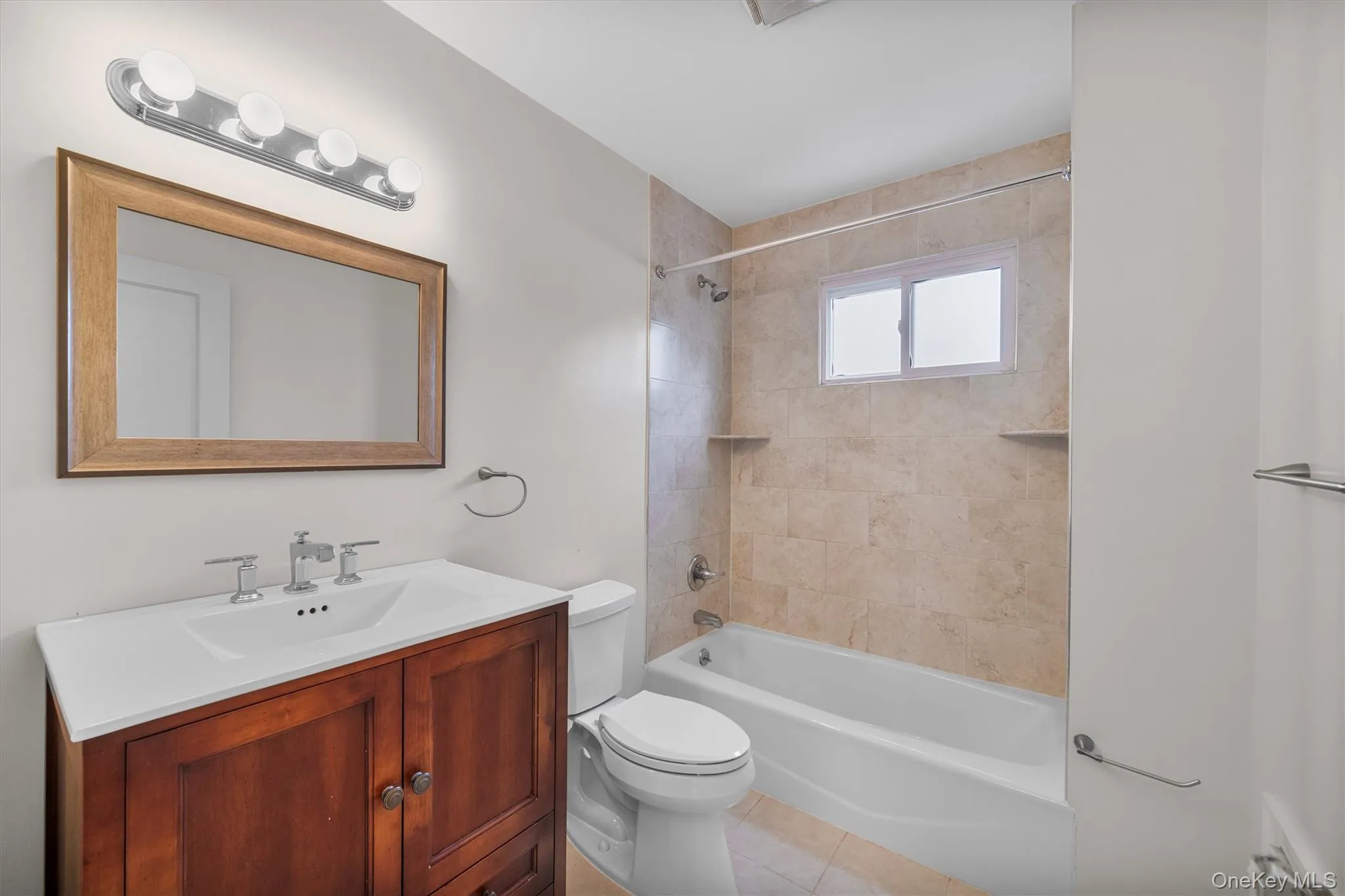 Full bath featuring vanity, washtub / shower combination, and light tile patterned floors Full bath featuring vanity, washtub / shower combination, and light tile patterned floors