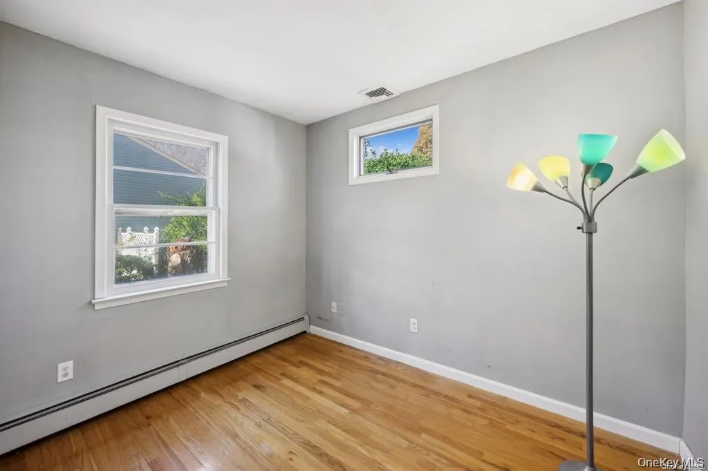 Spare room with a baseboard heating unit and light wood-type flooring Spare room with a baseboard heating unit and light wood-type flooring