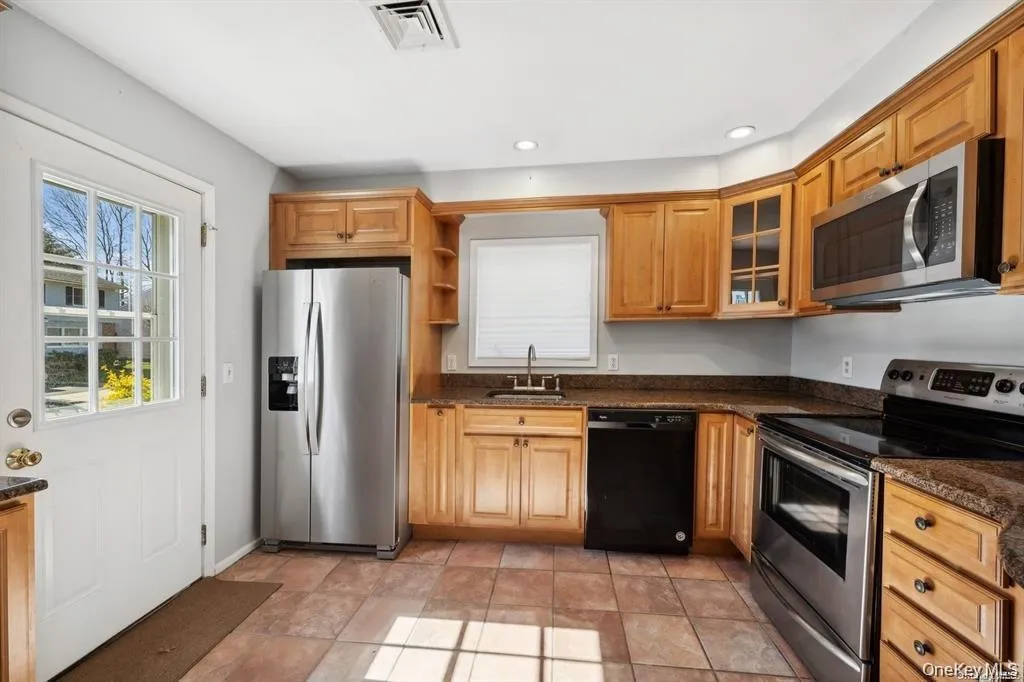 Kitchen featuring appliances with stainless steel finishes, glass insert cabinets, dark stone countertops, open shelves, and recessed lighting Kitchen featuring appliances with stainless steel finishes, glass insert cabinets, dark stone countertops, open shelves, and recessed lighting