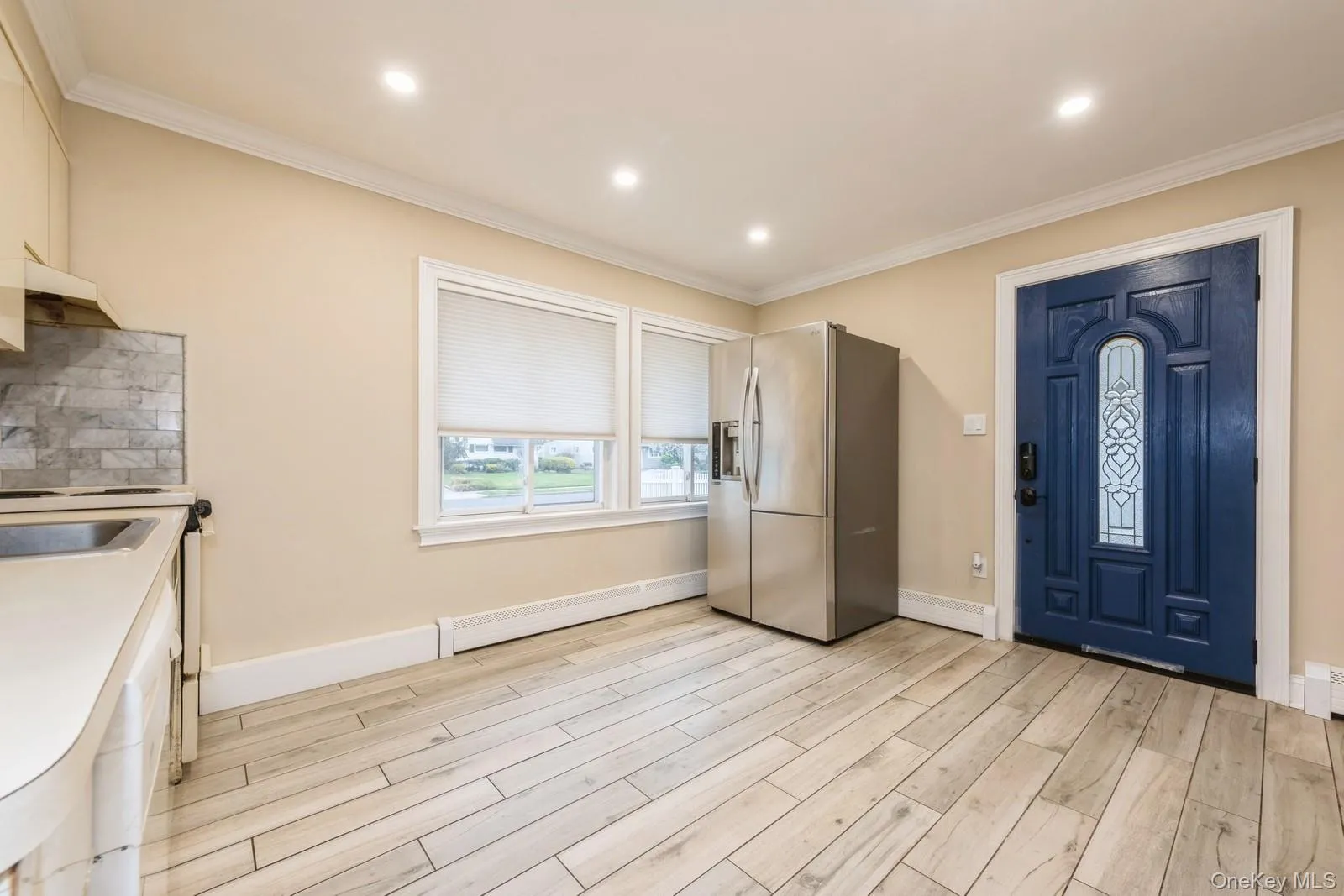 Kitchen with stainless steel fridge, light wood-style flooring, recessed lighting, light countertops, and crown molding Kitchen with stainless steel fridge, light wood-style flooring, recessed lighting, light countertops, and crown molding