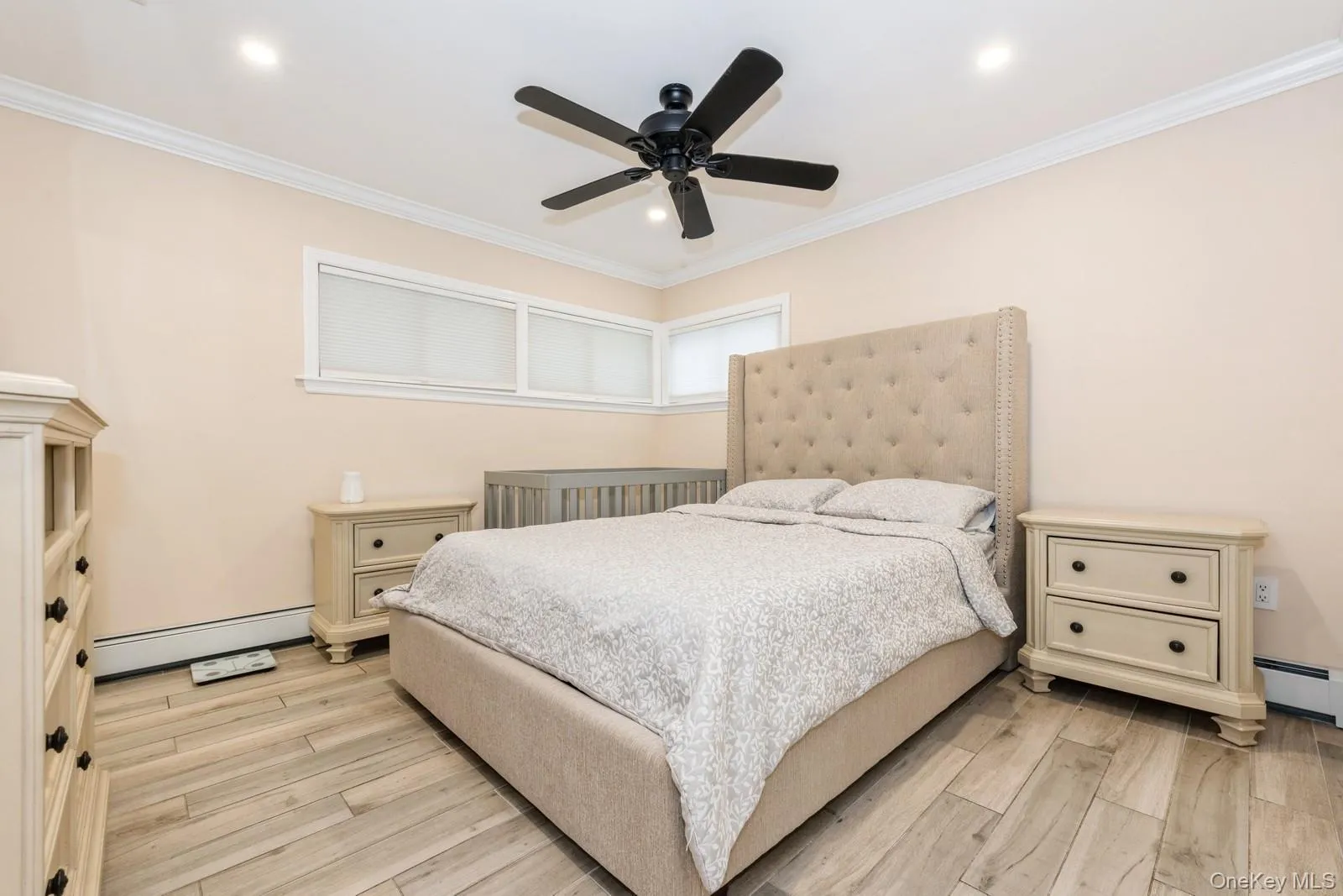Bedroom with light wood-type flooring, baseboard heating, crown molding, ceiling fan, and recessed lighting Bedroom with light wood-type flooring, baseboard heating, crown molding, ceiling fan, and recessed lighting
