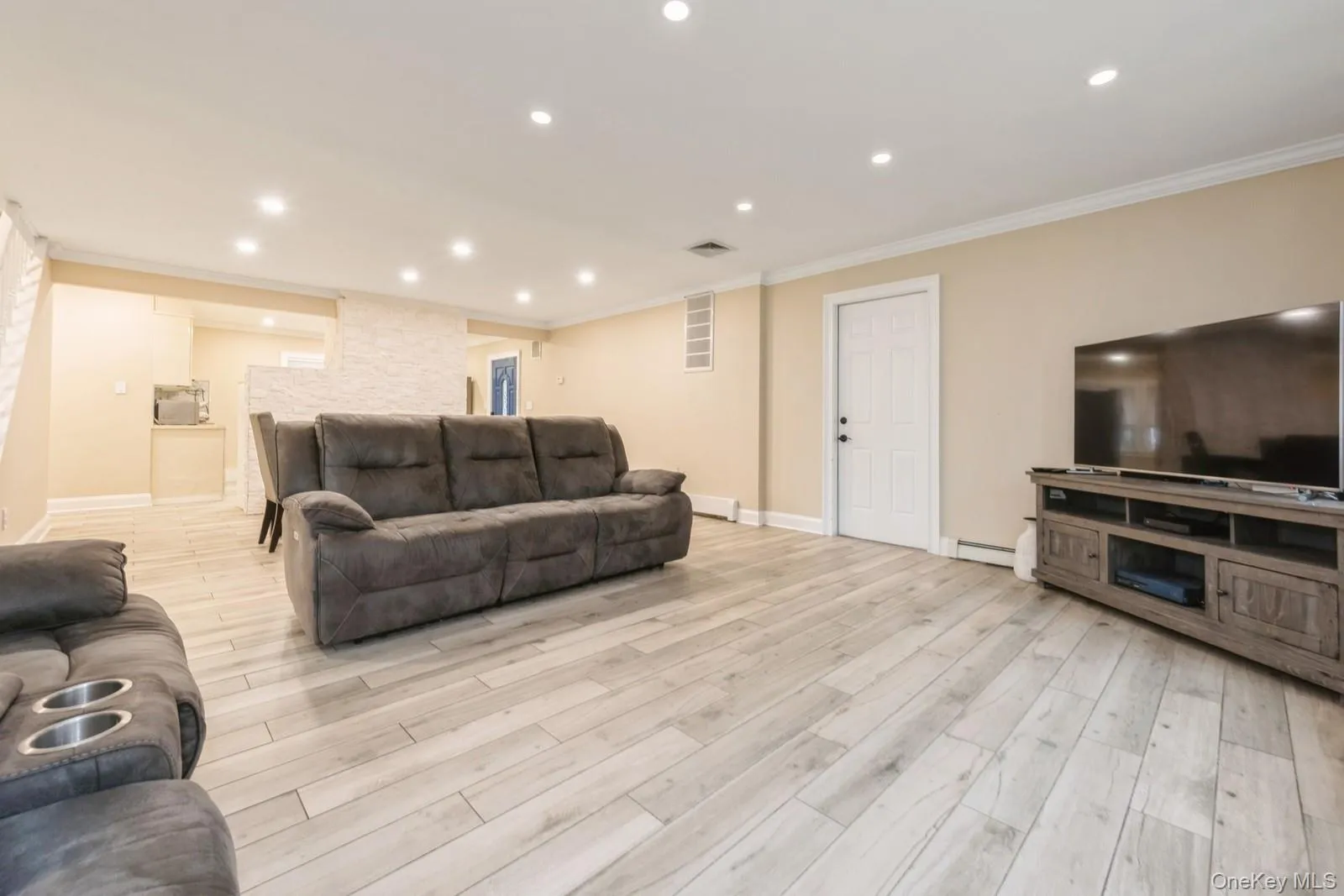 Living room with recessed lighting, crown molding, light wood-style flooring, baseboard heating, and a baseboard radiator Living room with recessed lighting, crown molding, light wood-style flooring, baseboard heating, and a baseboard radiator