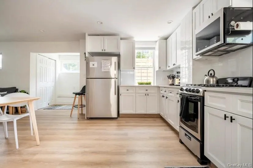 Kitchen with appliances with stainless steel finishes, white cabinetry, light countertops, light wood-type flooring, and recessed lighting Kitchen with appliances with stainless steel finishes, white cabinetry, light countertops, light wood-type flooring, and recessed lighting