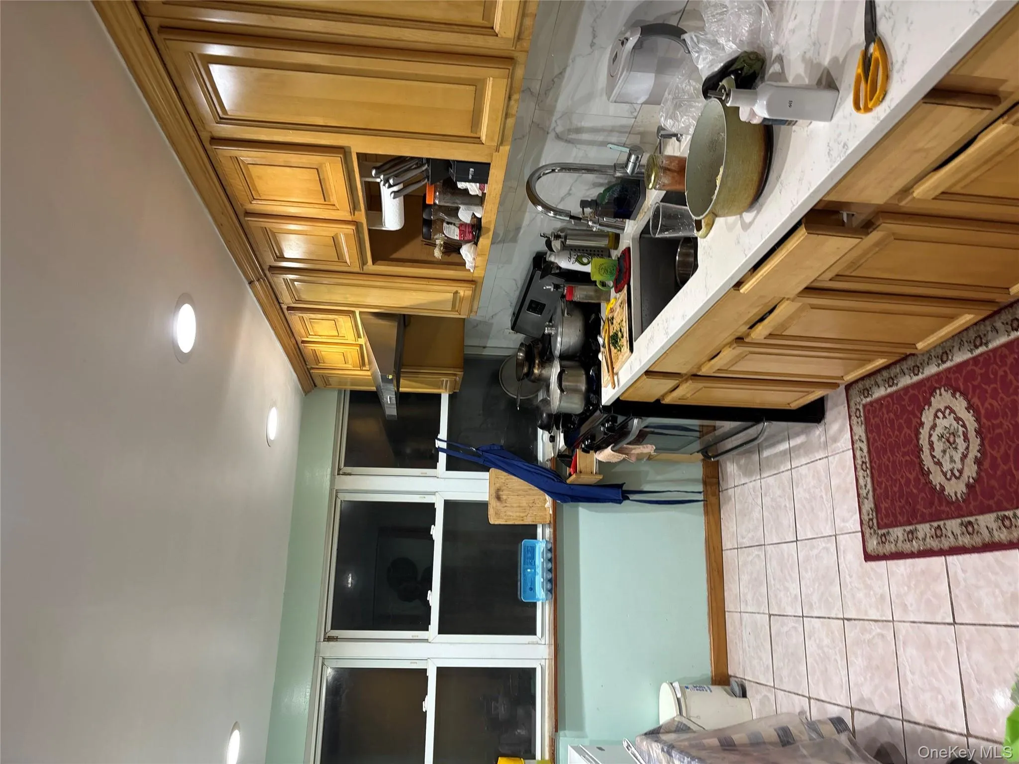 Kitchen with range, light tile patterned floors, brown cabinetry, light stone counters, and decorative backsplash Kitchen with range, light tile patterned floors, brown cabinetry, light stone counters, and decorative backsplash